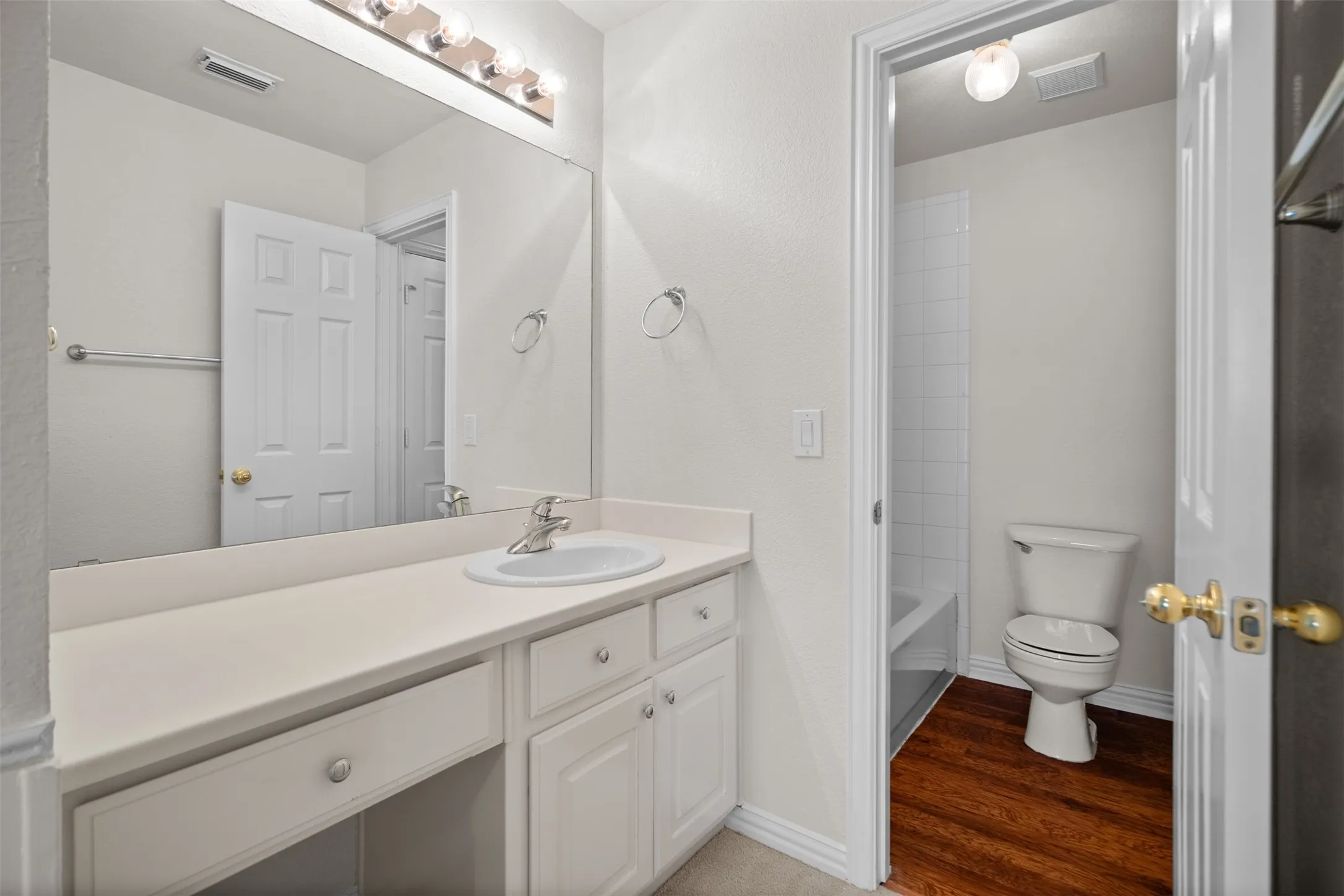 Vanity with an integrated sink, built-in cabinetry, and a full-width mirror with overhead lighting