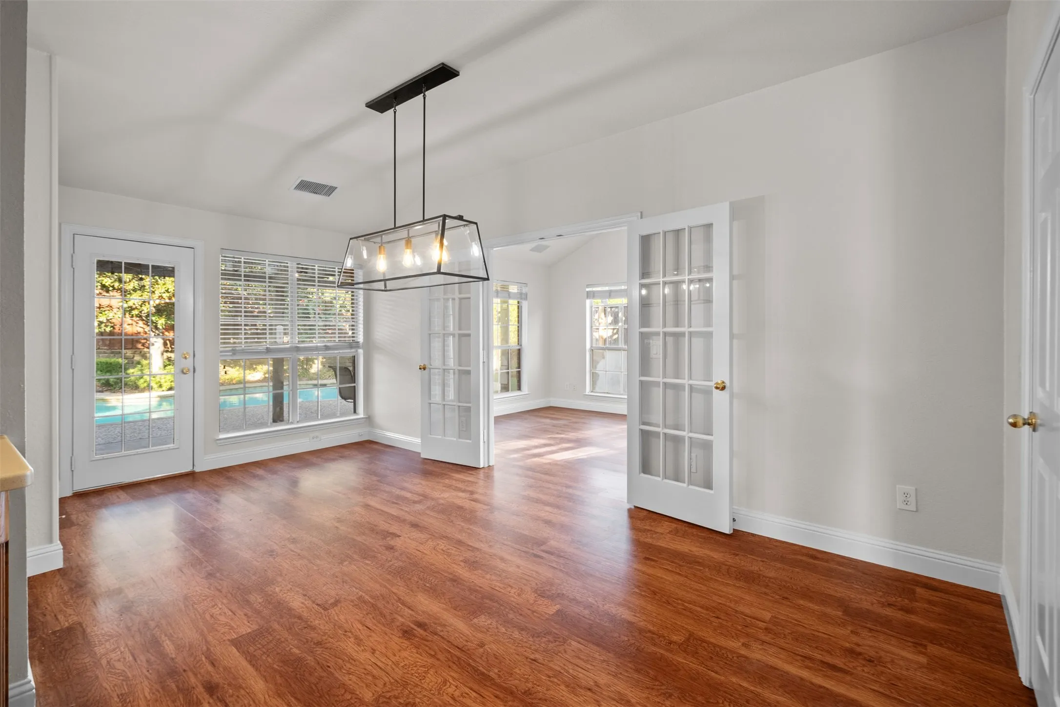 Wood-finish flooring, white walls, and a modern rectangular chandelier