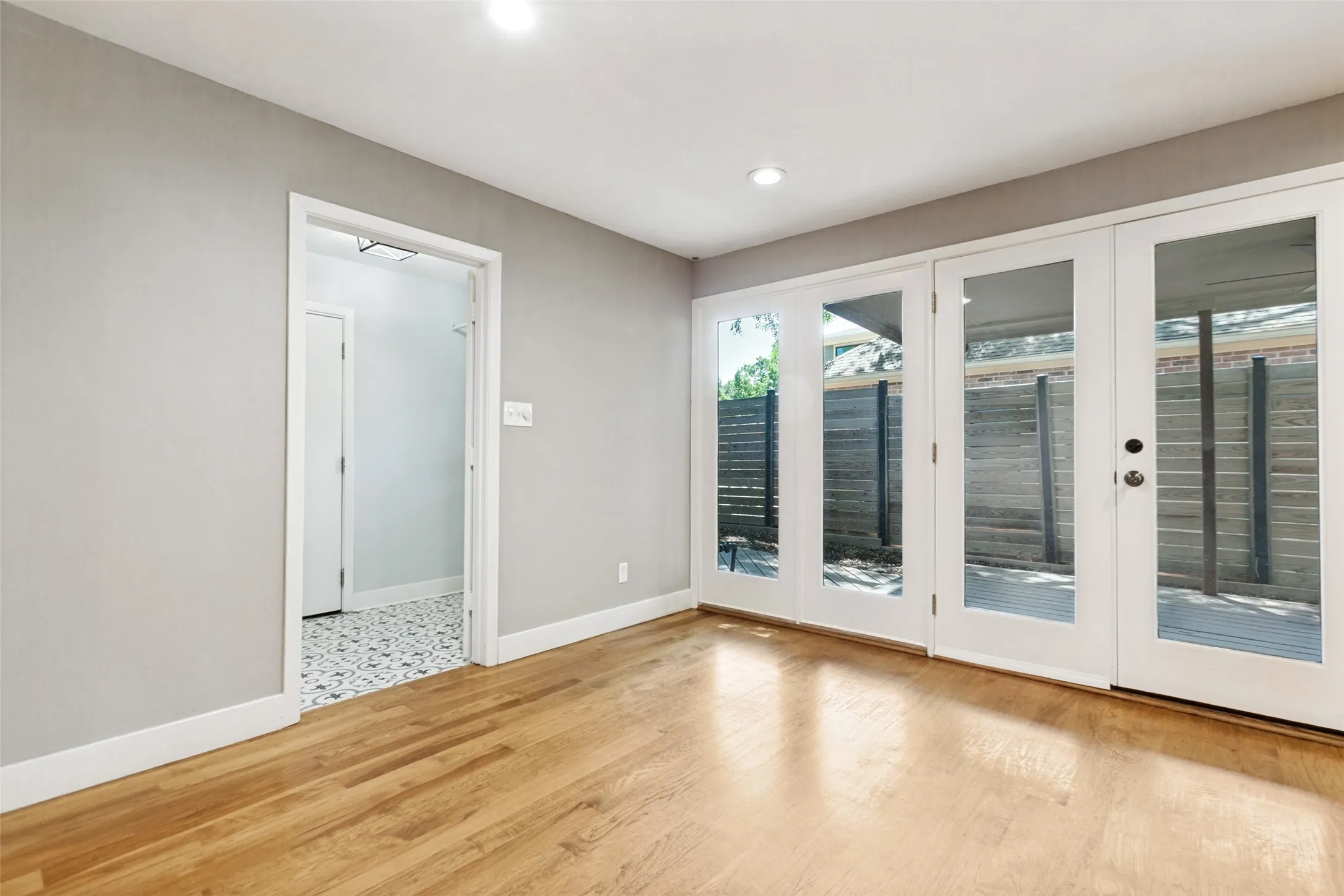 Wood-finish flooring with white baseboards, recessed ceiling lighting, and a neutral wall color