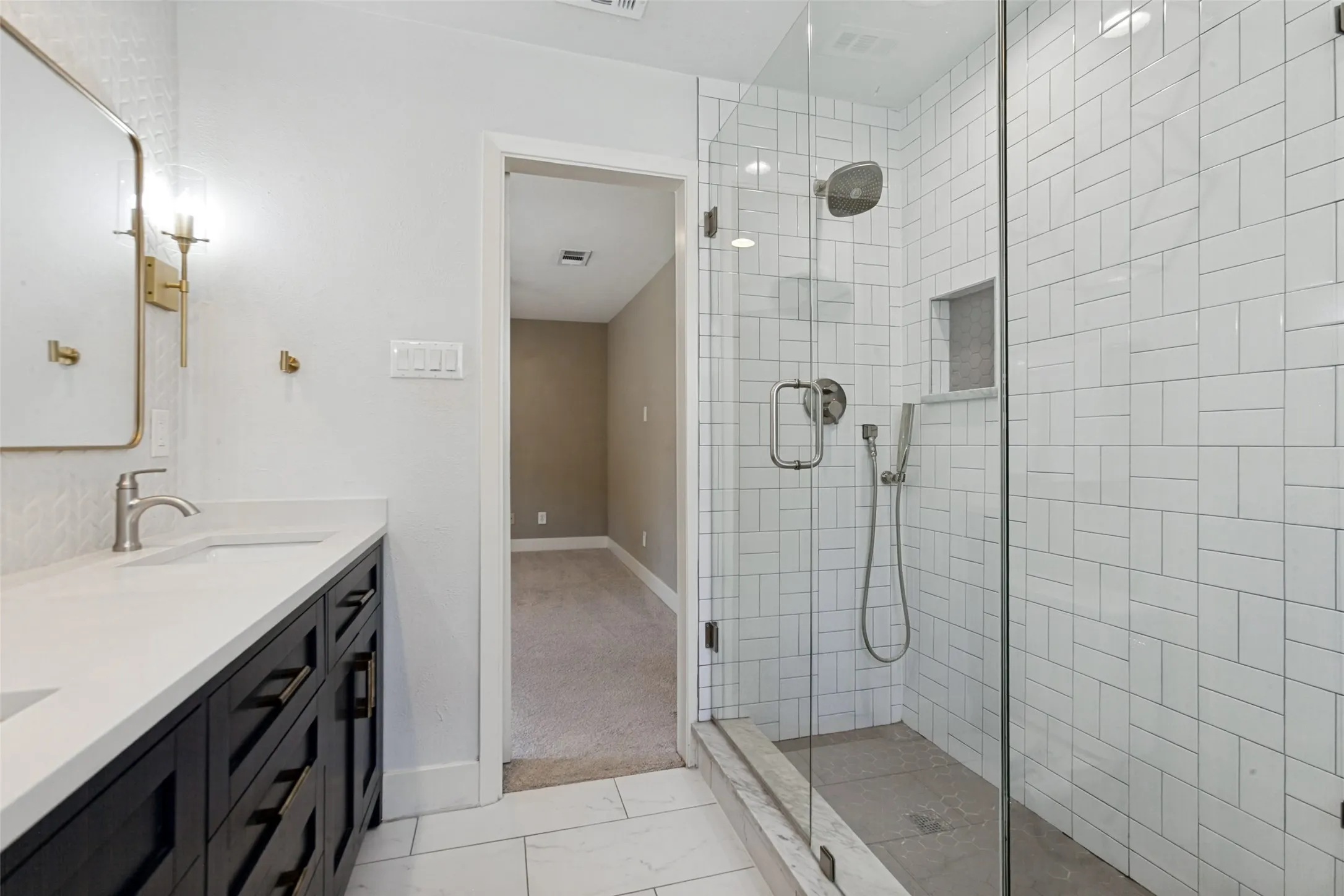 Frameless glass shower enclosure with white subway tile, a built-in shower niche, and a rain shower head
