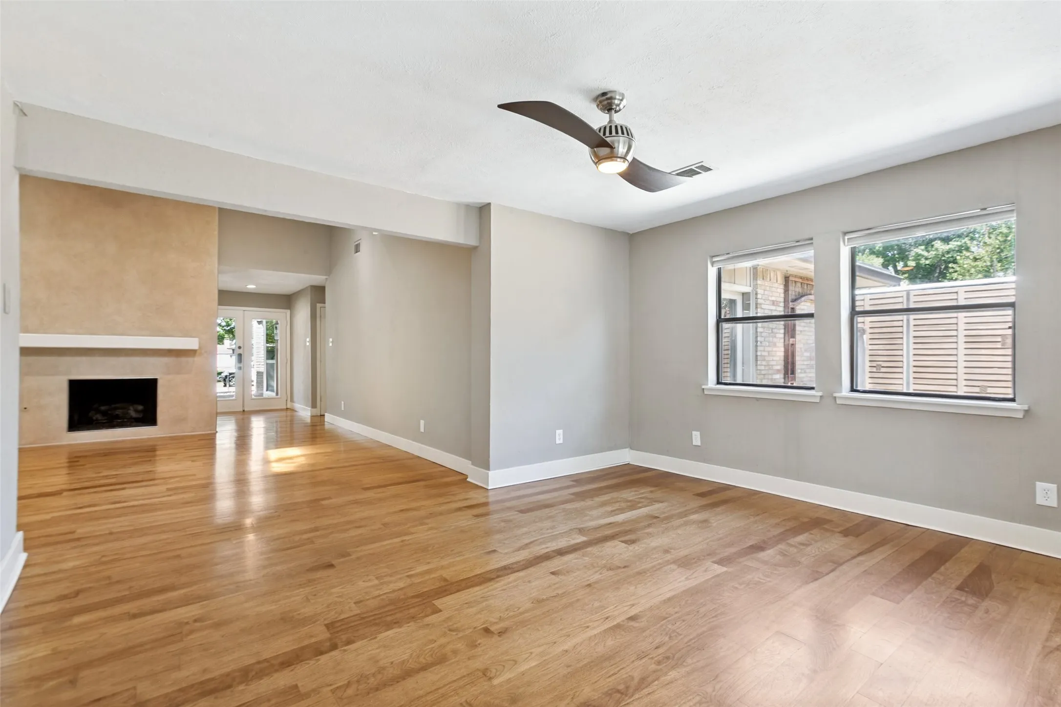 Hardwood flooring, contemporary ceiling fan, fireplace with mantel, French doors, multiple windows