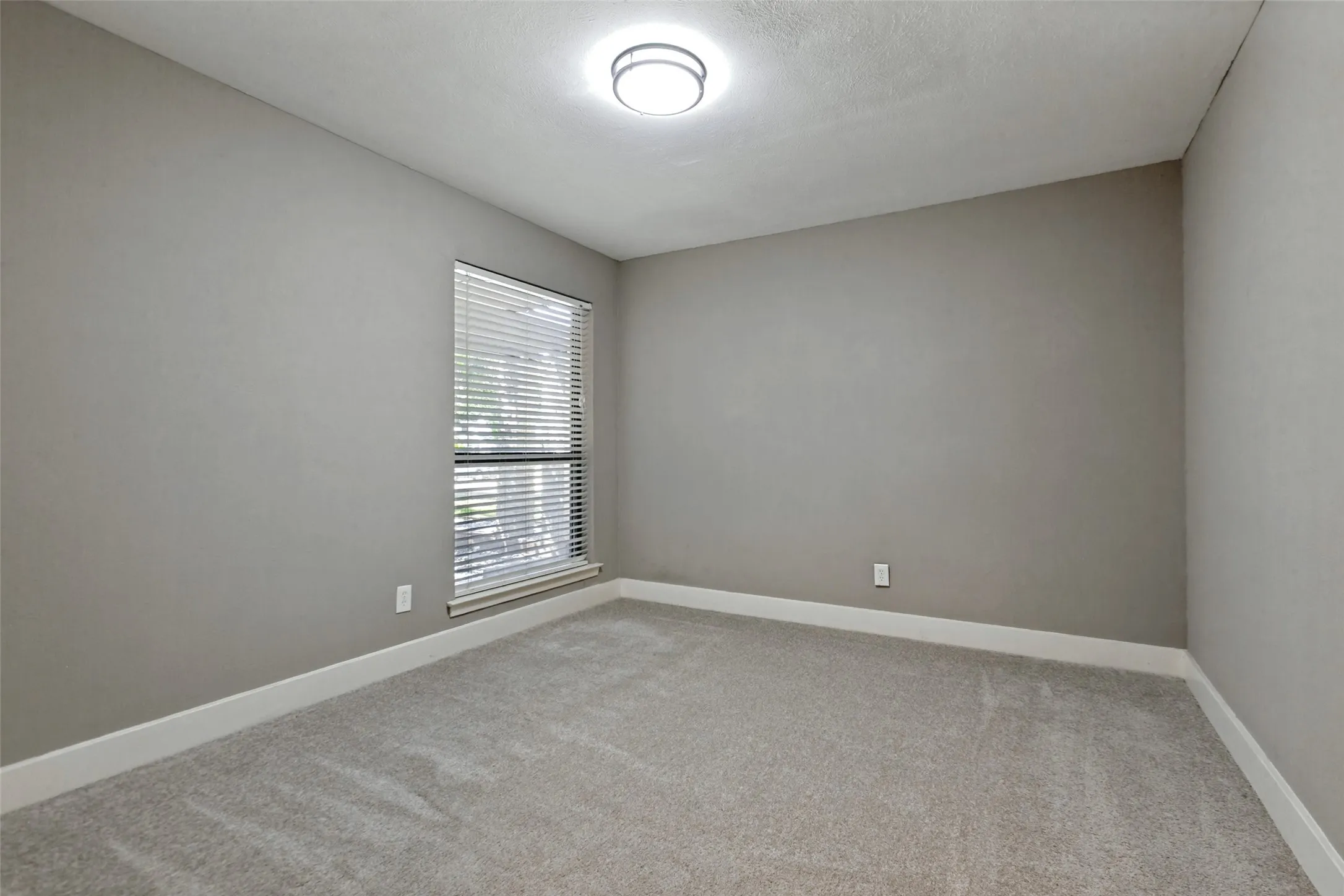 Recessed window with horizontal blinds, neutral wall paint, white trim, and light-colored carpeting