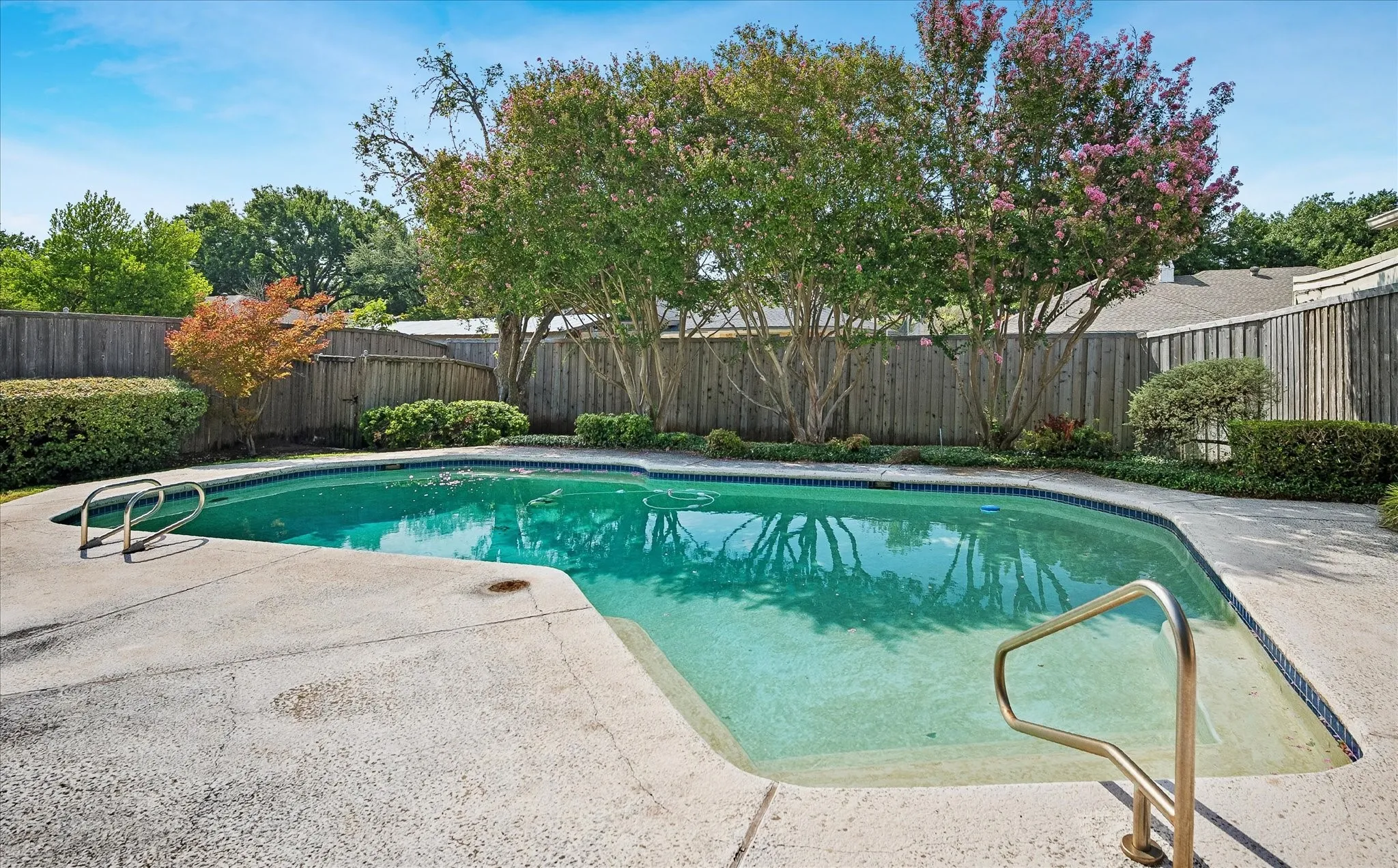 Freeform pool with a shaded, fully fenced backyard