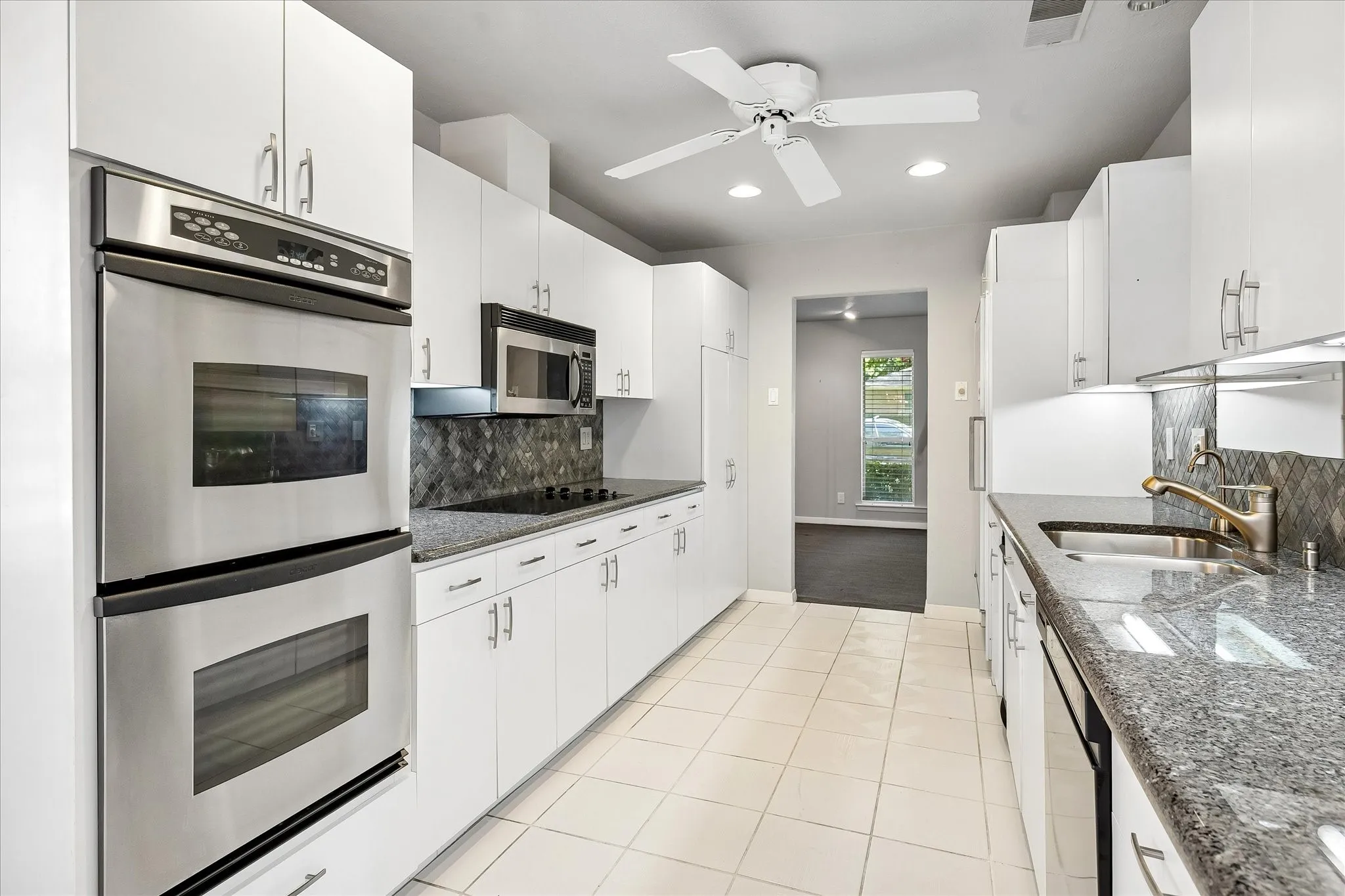 Long galley kitchen with abundant cabinetry and granite countertops throughout.