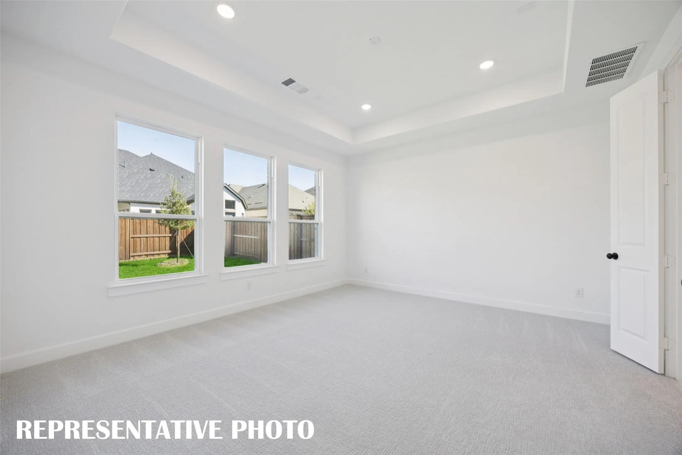 Your new light filled owner's suite offers high ceilings, plush carpeting and a wall of windows creating the perfect retreat.  REPRESENTATIVE PHOTO