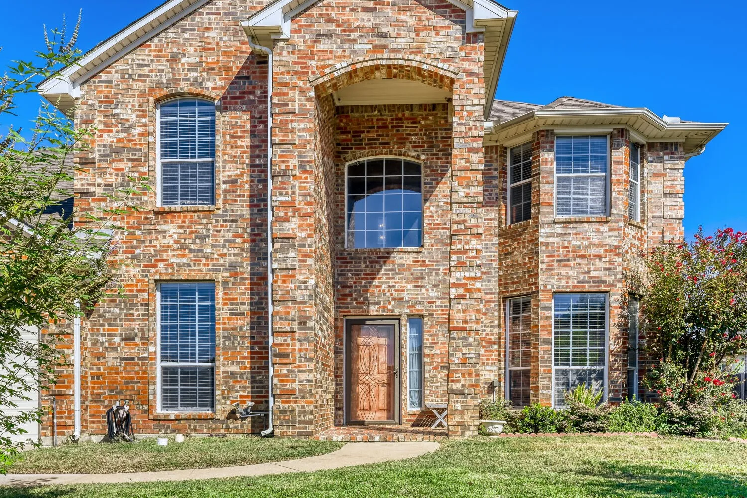 Brick exterior with a prominent arched entrance, multiple transom windows, and a bay window feature