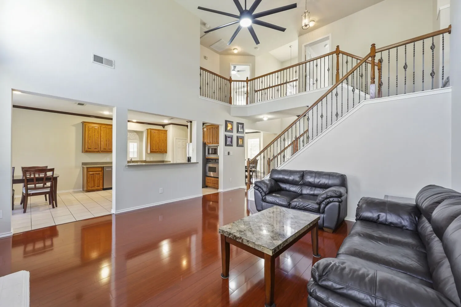 Vaulted ceiling, wood-finish flooring, staircase with wrought iron balusters, upper-level landing, and recessed lighting