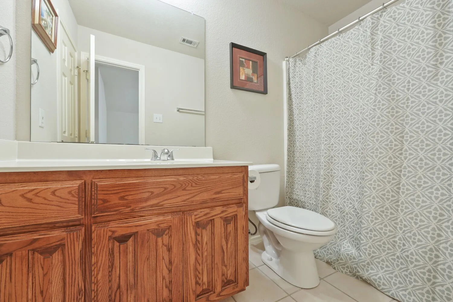 Wood-finish vanity with an integrated sink, polished chrome faucet, and full-width mirror
