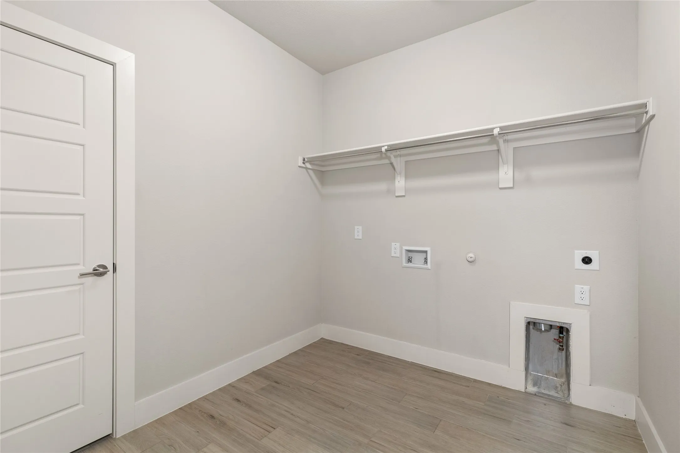 Wood-finish flooring, white paneled door, built-in shelving, and laundry hookups