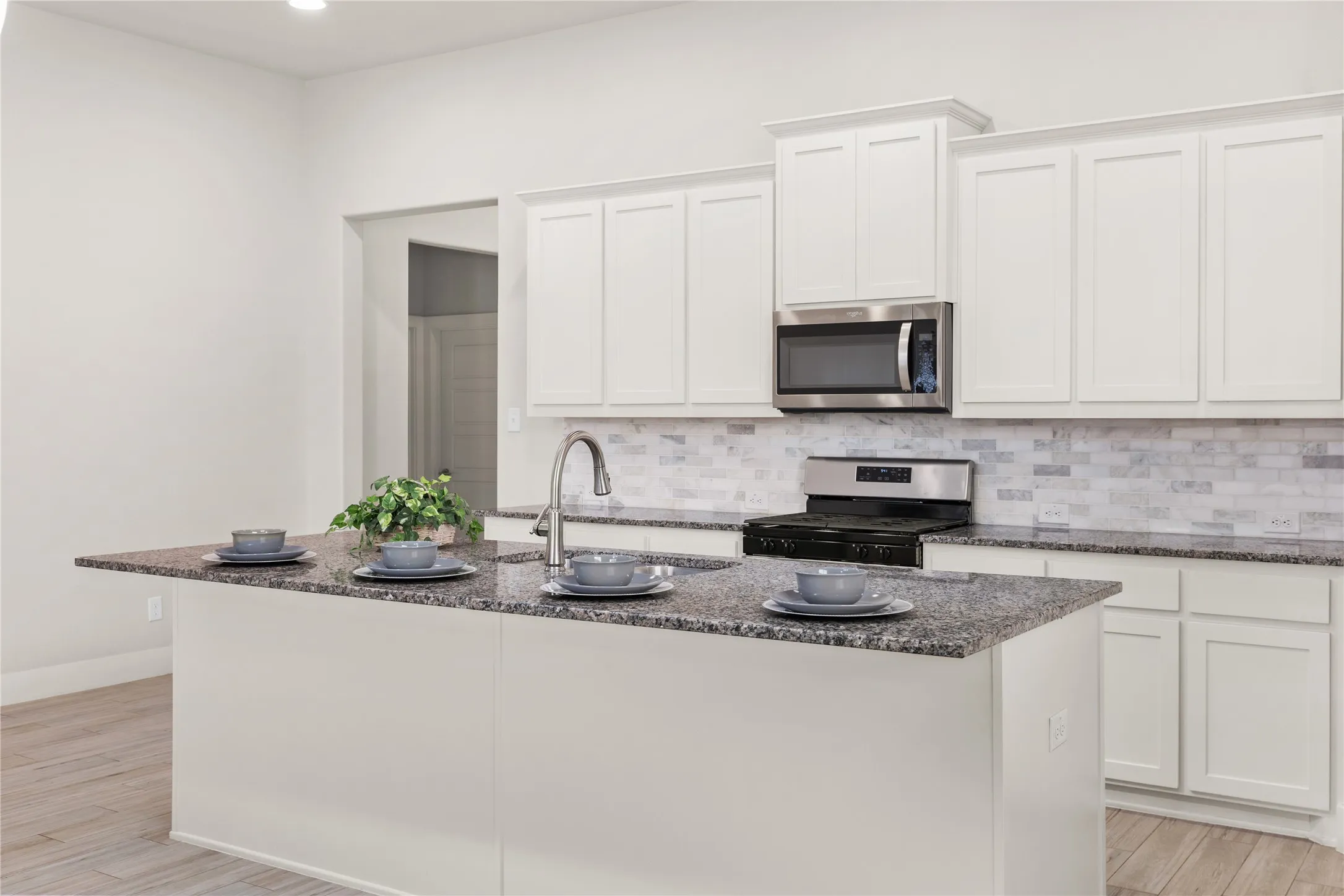 Kitchen featuring a center island, white cabinetry, granite countertops, stainless steel appliances, and a tile backsplash
