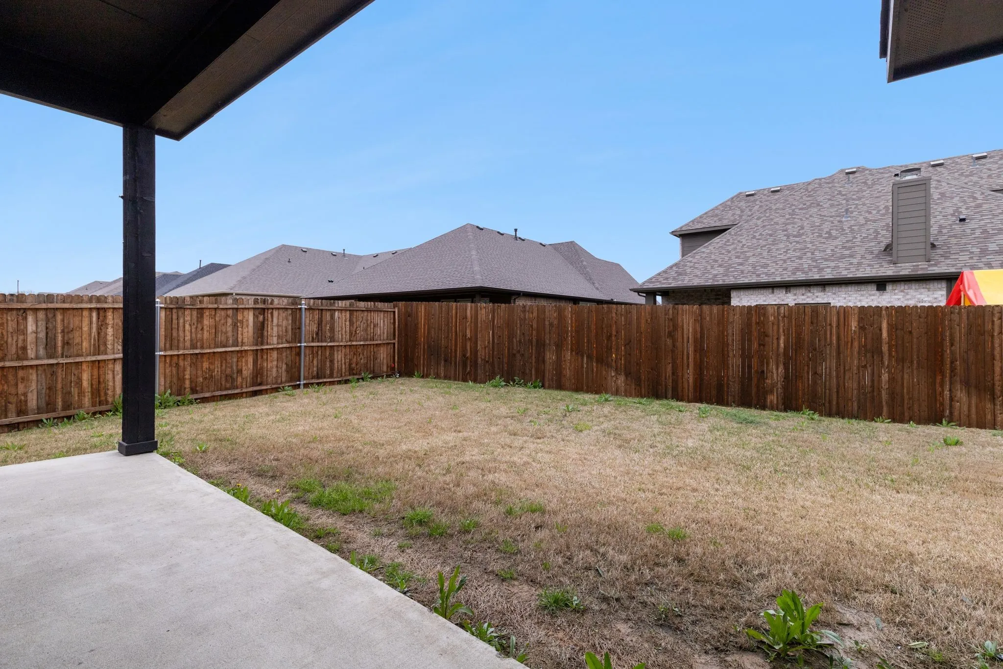 Concrete patio with an adjacent grass area and a wood privacy fence