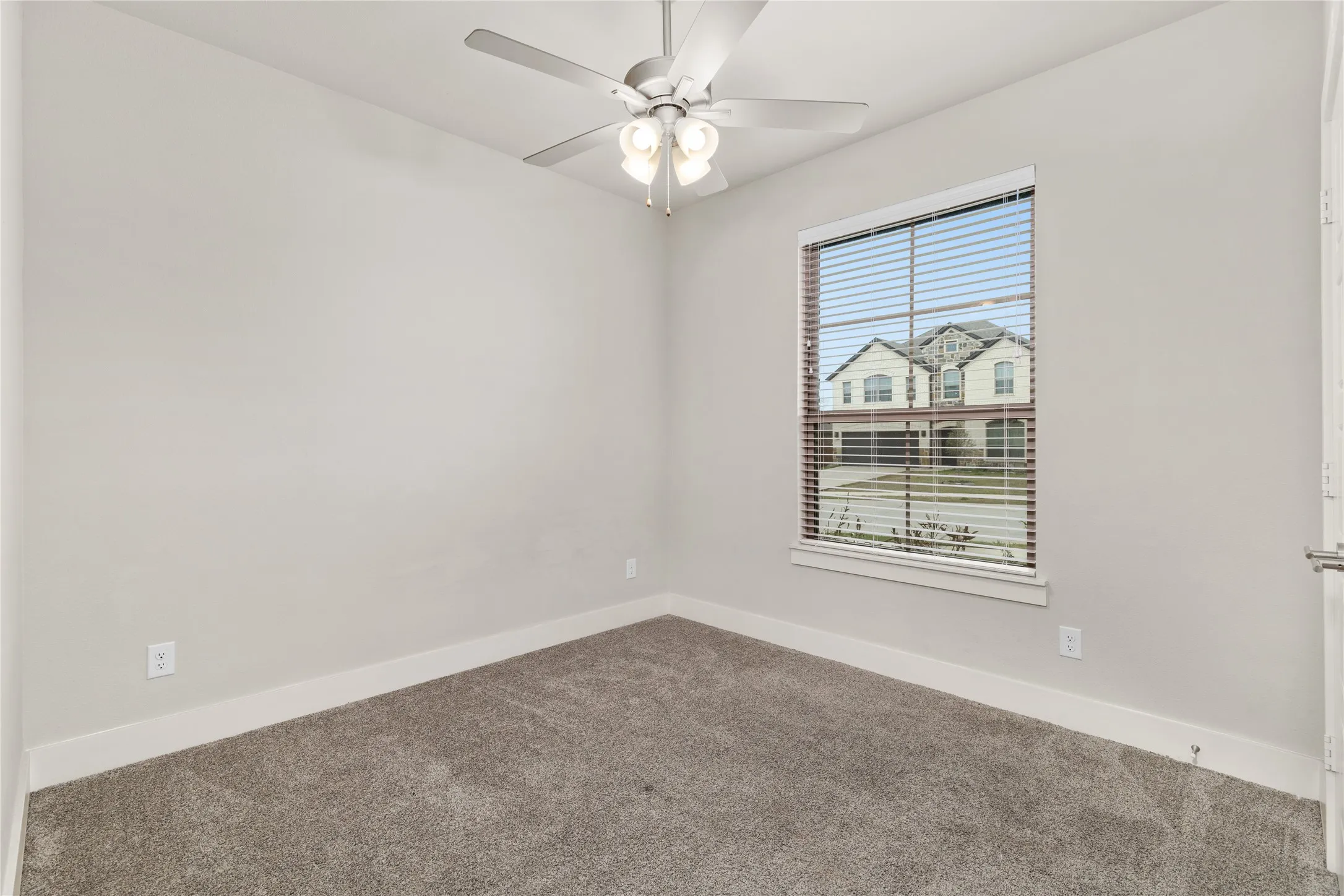 Wall-to-wall carpeting, ceiling fan with integrated lighting, and a single window with blinds
