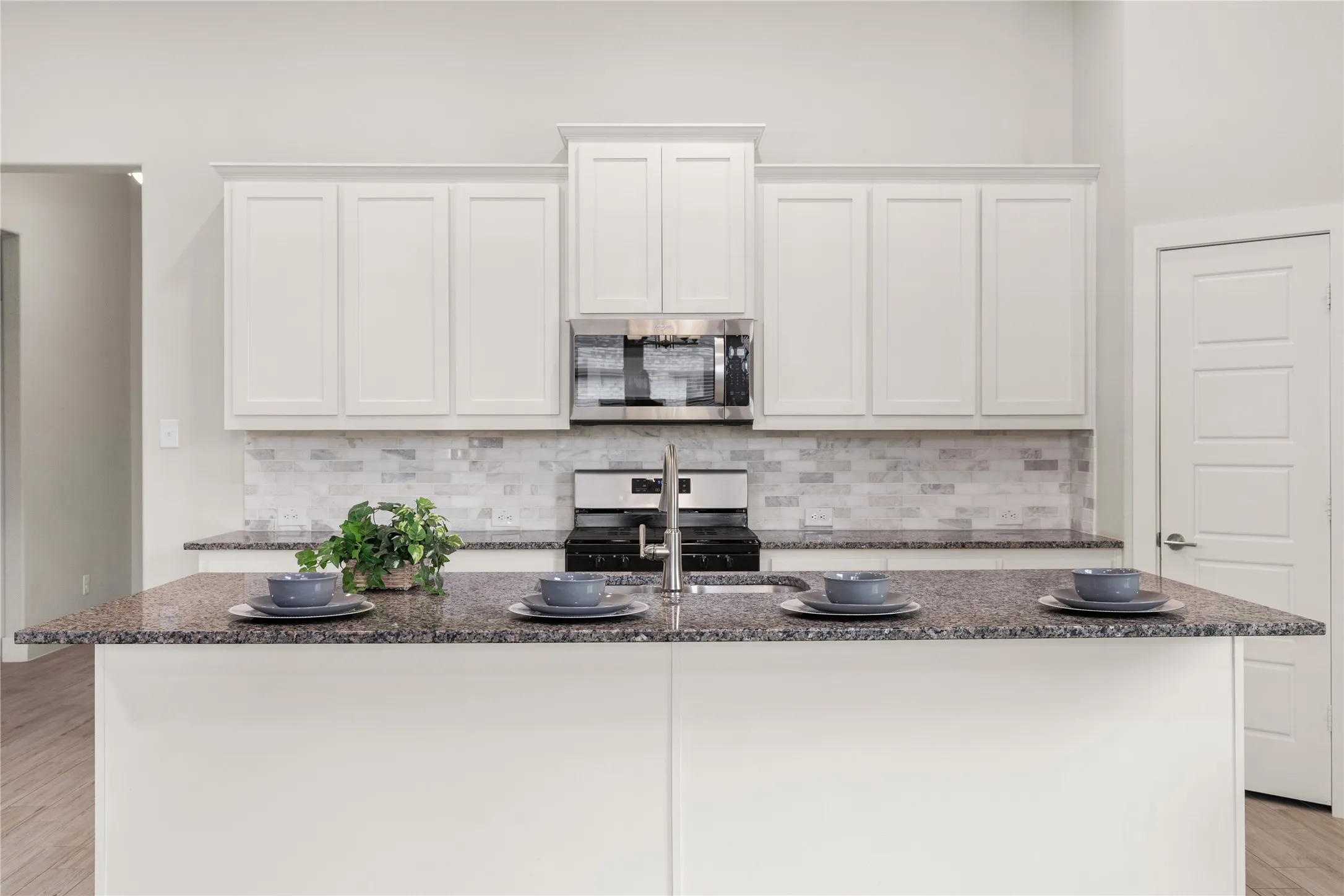 Kitchen featuring a central island, white shaker cabinetry, stainless steel appliances, and a mosaic tile backsplash