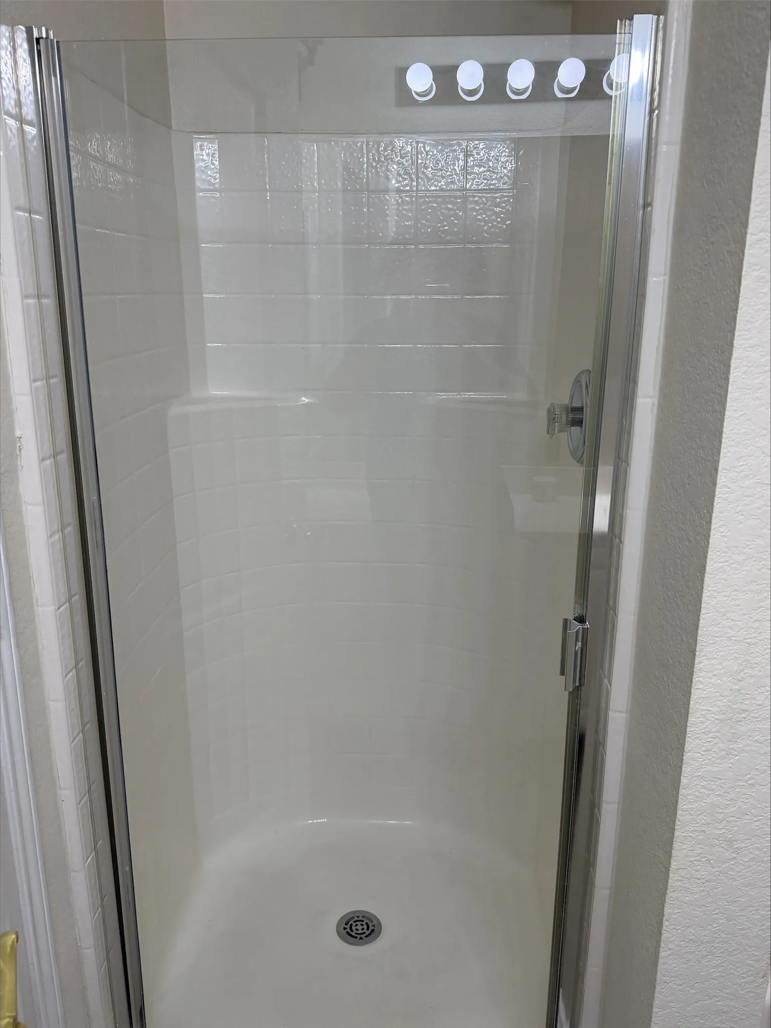 Walk-in shower featuring a chrome showerhead, a built-in seat, and a clear glass enclosure