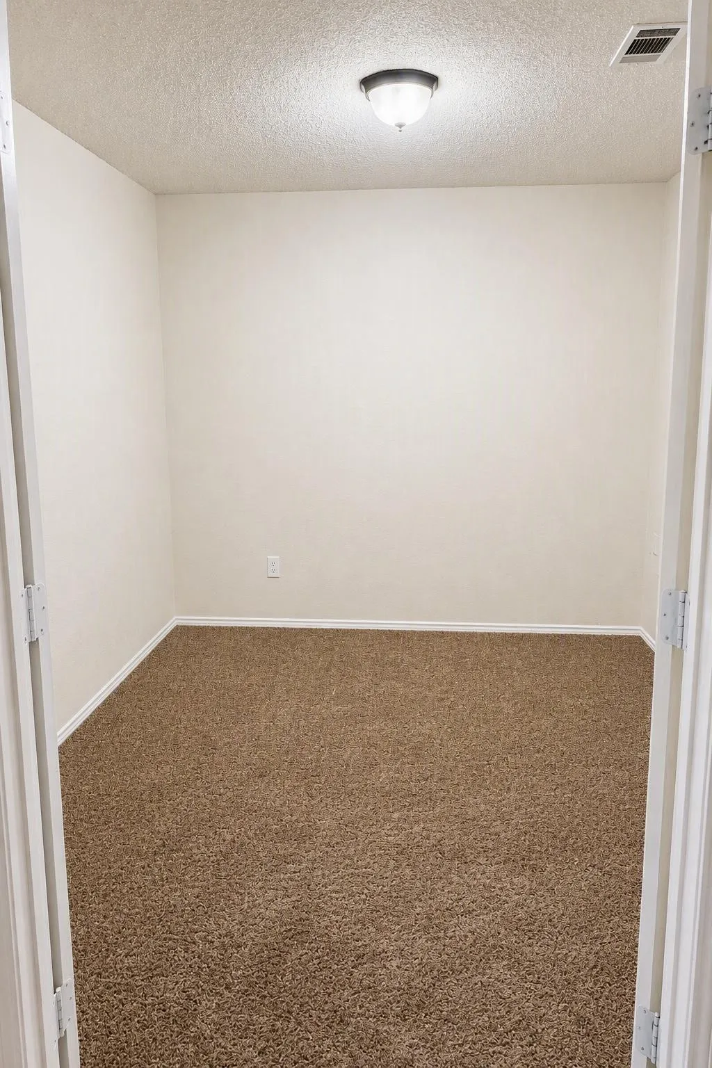 Neutral-toned carpeting, white painted walls, and an overhead flush-mount light fixture