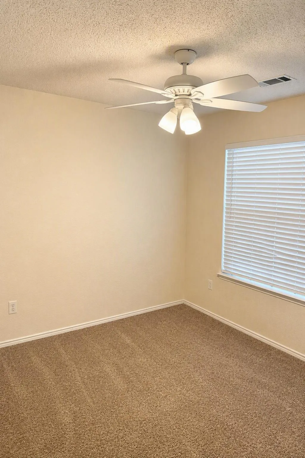 Textured ceiling with a ceiling fan light fixture, neutral wall paint, and carpet flooring