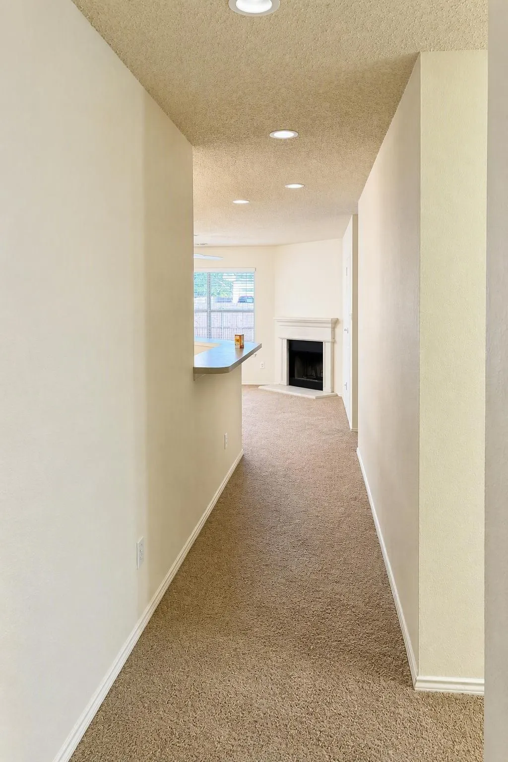 Recessed lighting illuminates the hallway with neutral-toned walls and carpet flooring