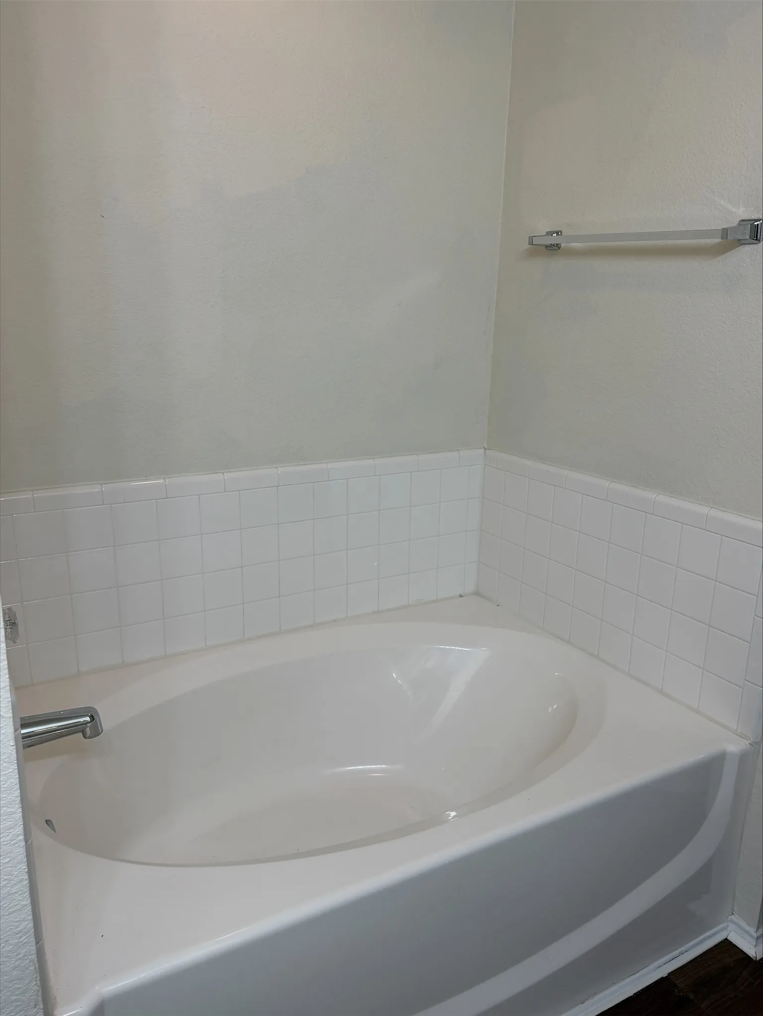 Built-in soaking tub with surrounding white tile wainscoting and chrome fixtures