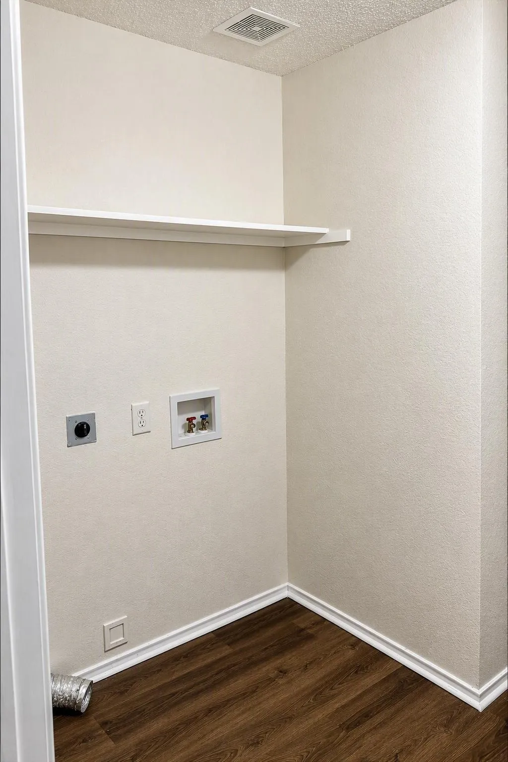 Dedicated utility area featuring a built-in shelf, wood-finish flooring, and essential appliance hookups