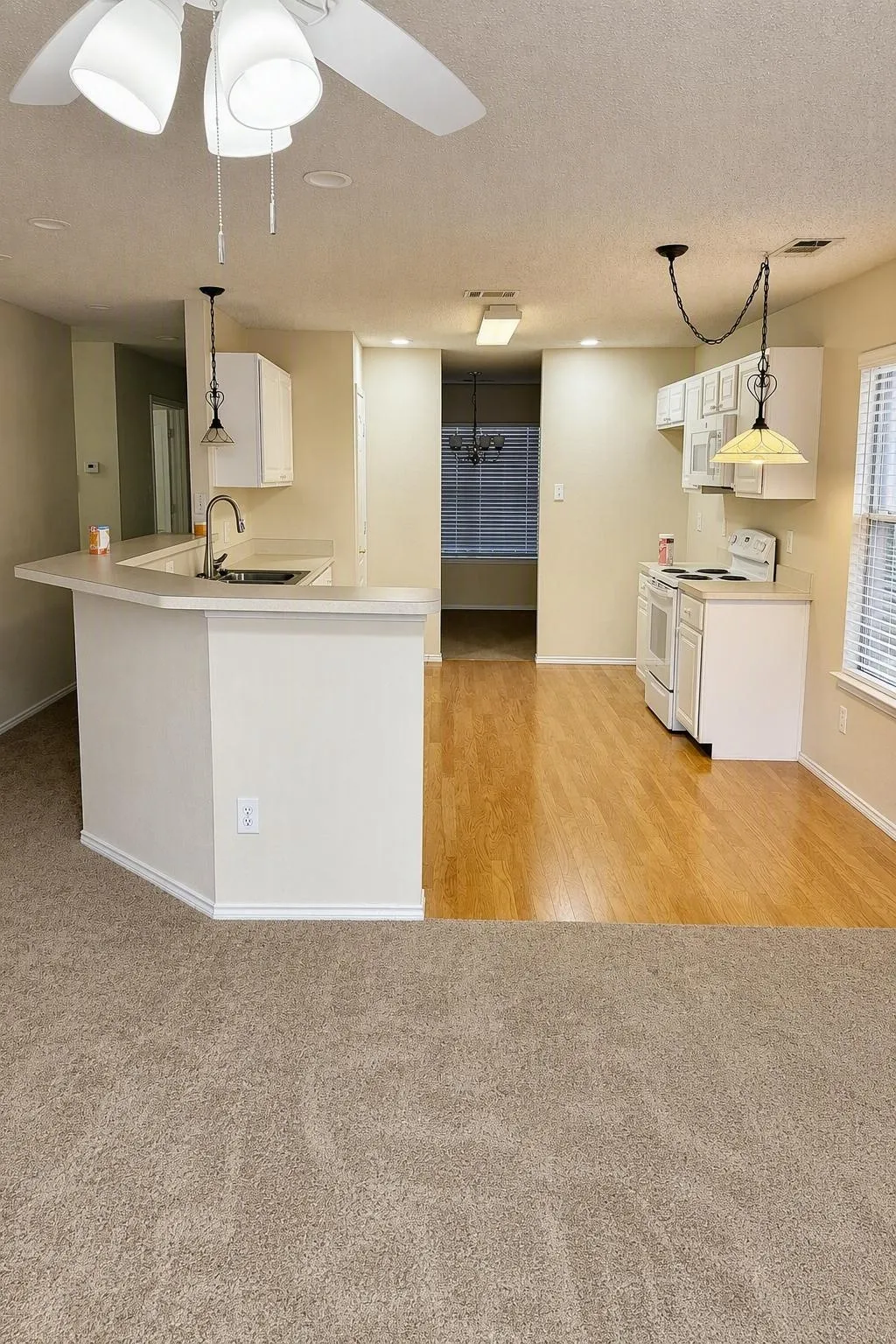 Kitchen with white cabinetry, light-toned countertops, and wood-finish flooring