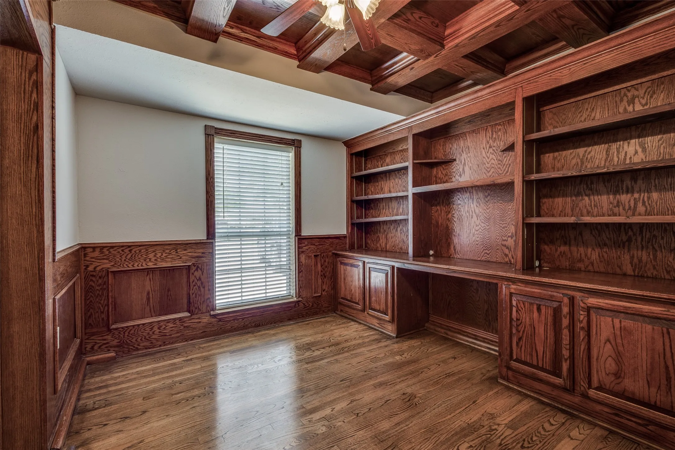 Unfurnished office featuring ceiling fan, coffered ceiling, dark wood-type flooring, and beam ceiling