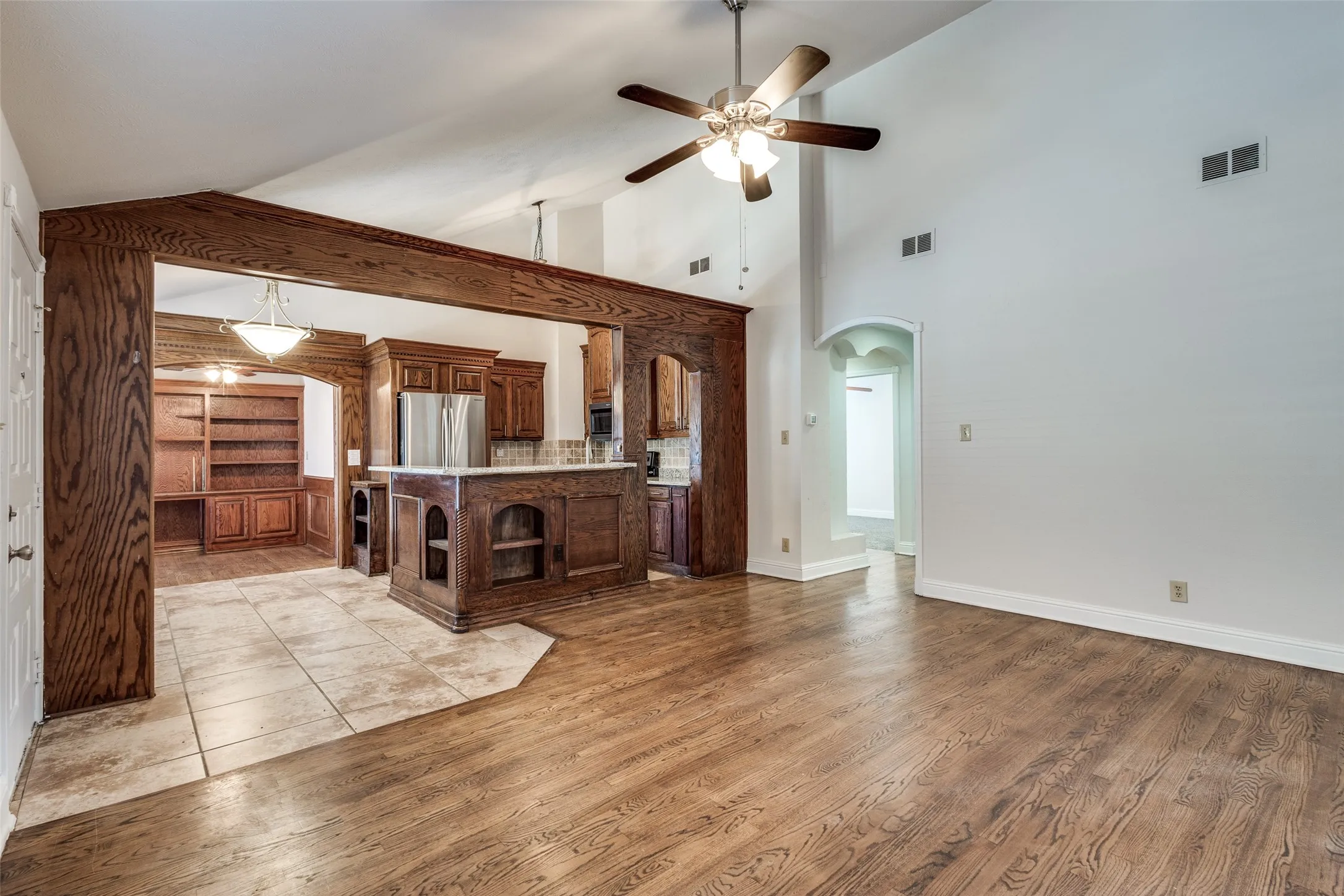 Kitchen featuring ceiling fan, light hardwood / wood-style flooring, pendant lighting, high vaulted ceiling, and stainless steel refrigerator