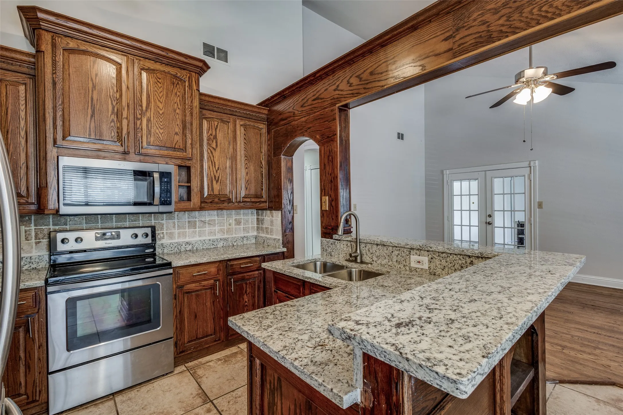Kitchen featuring sink, light hardwood / wood-style floors, tasteful backsplash, ceiling fan, and stainless steel appliances