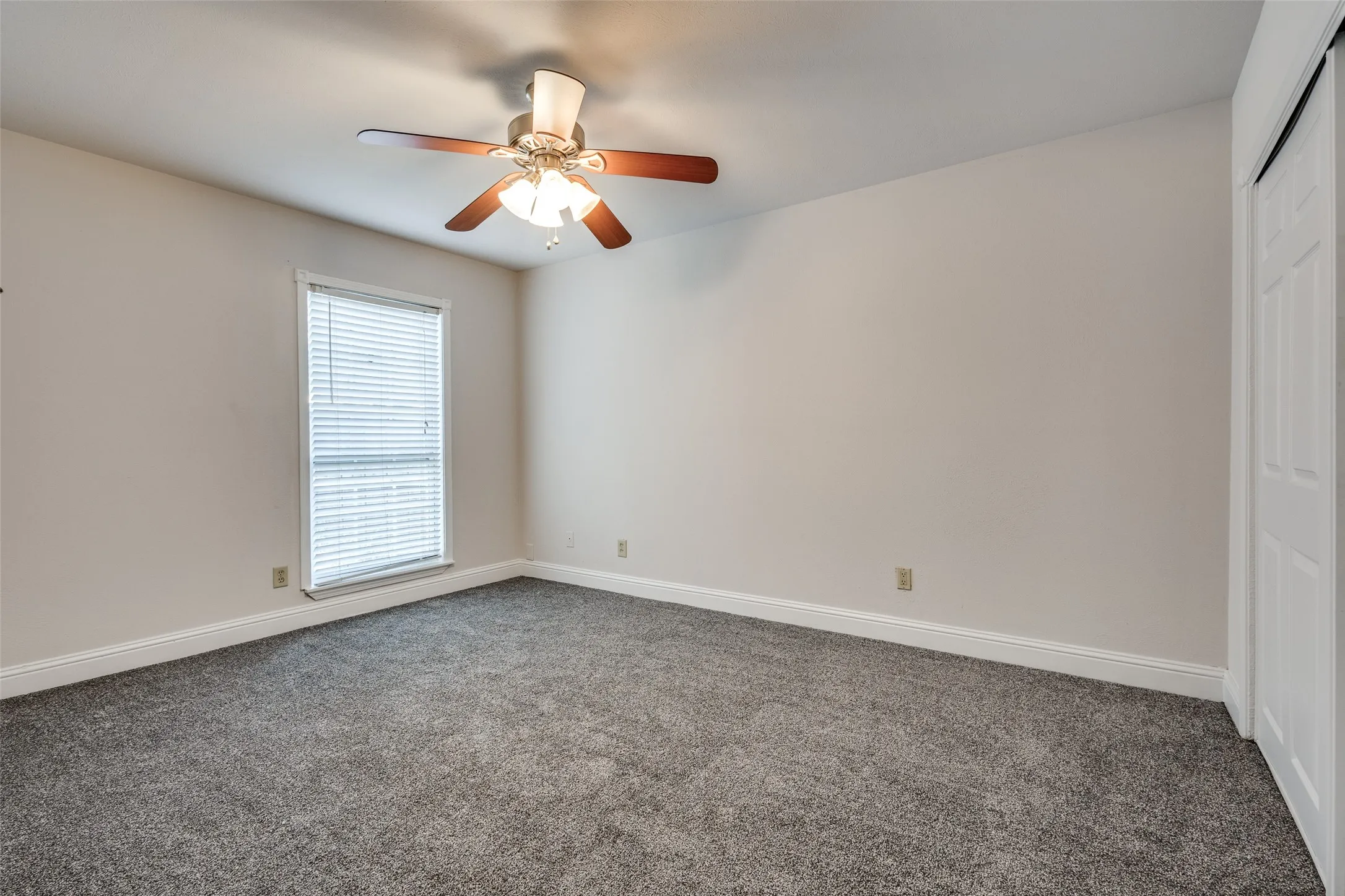 Empty room featuring ceiling fan and carpet floors