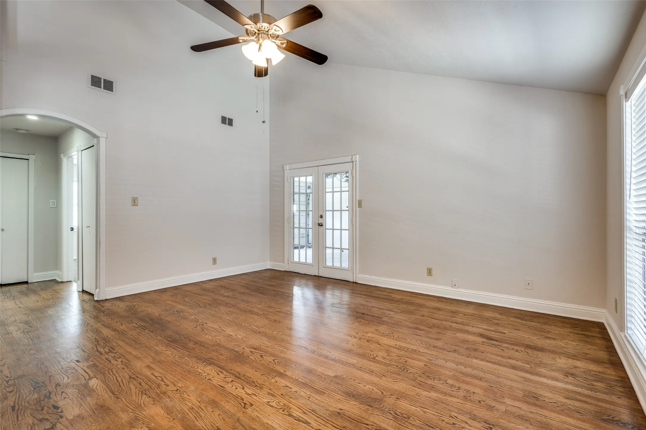 Spare room featuring ceiling fan, high vaulted ceiling, hardwood / wood-style flooring, and french doors