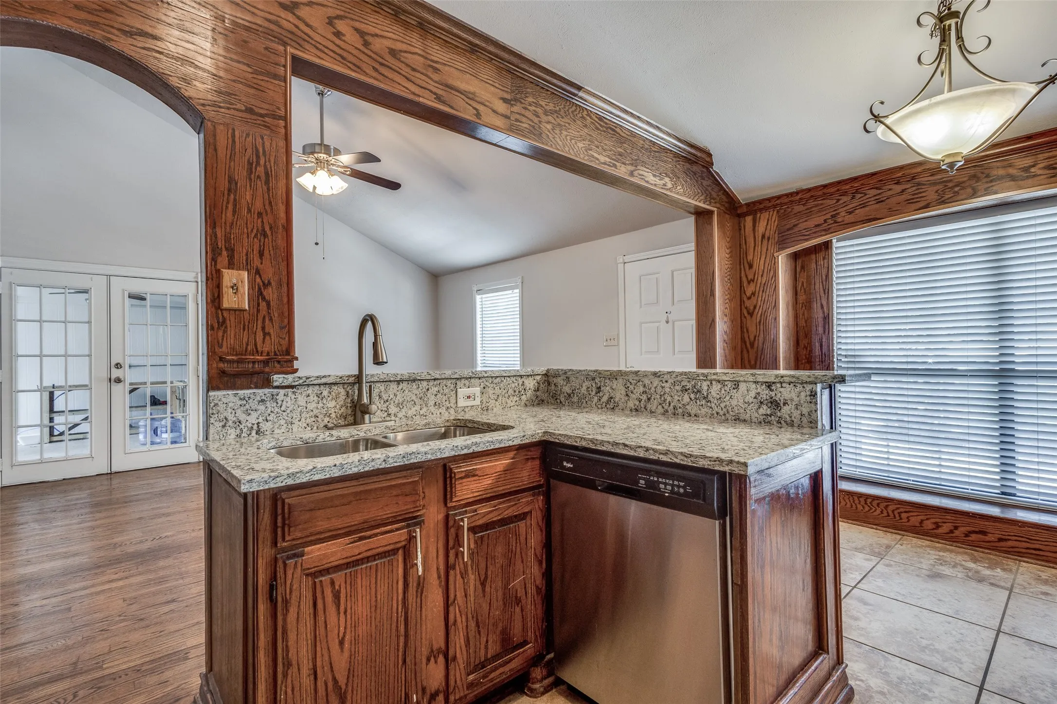 Kitchen featuring light hardwood / wood-style flooring, stainless steel dishwasher, sink, ceiling fan, and vaulted ceiling