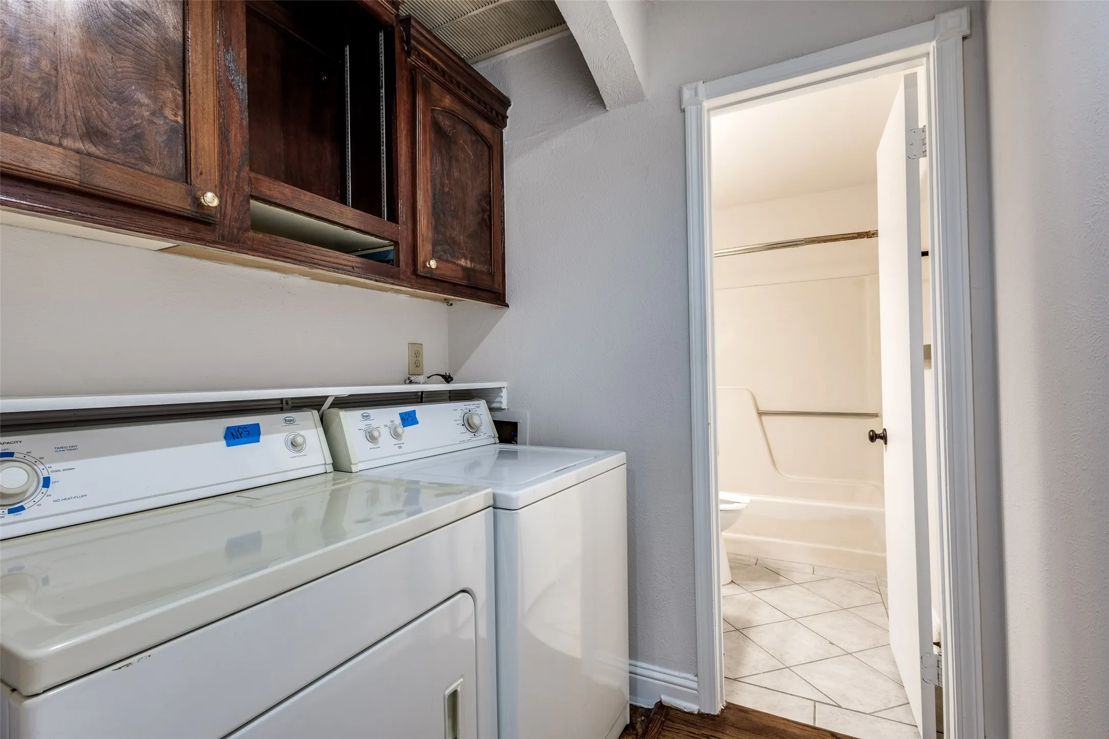 Washroom with tile patterned flooring, washer and dryer, and cabinets