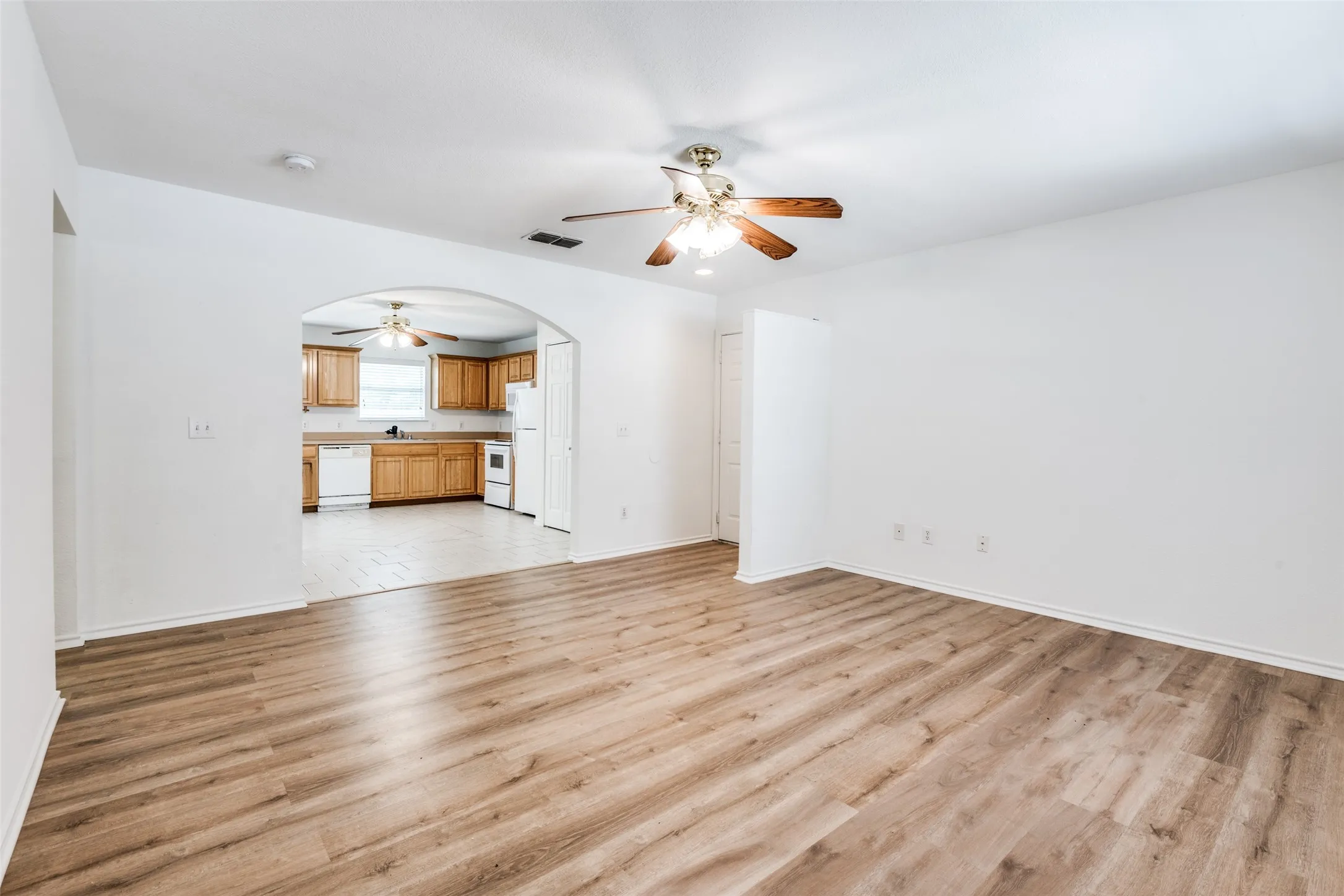 Unfurnished living room featuring ceiling fan, sink, and light wood-type flooring