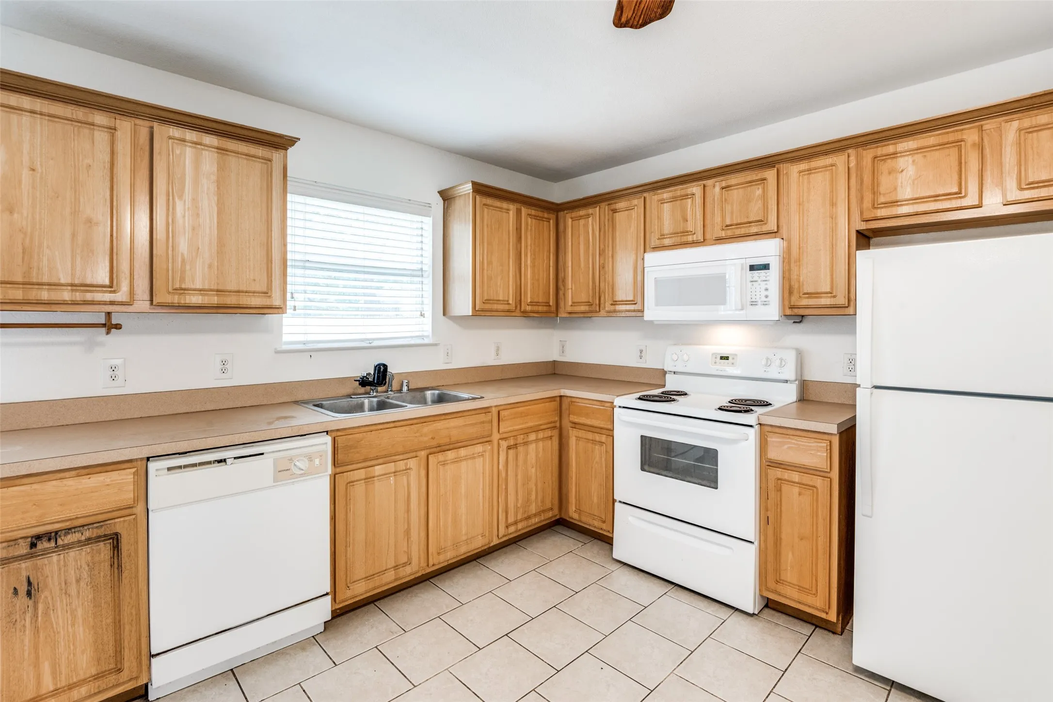 Kitchen featuring white appliances, light tile patterned flooring, and sink