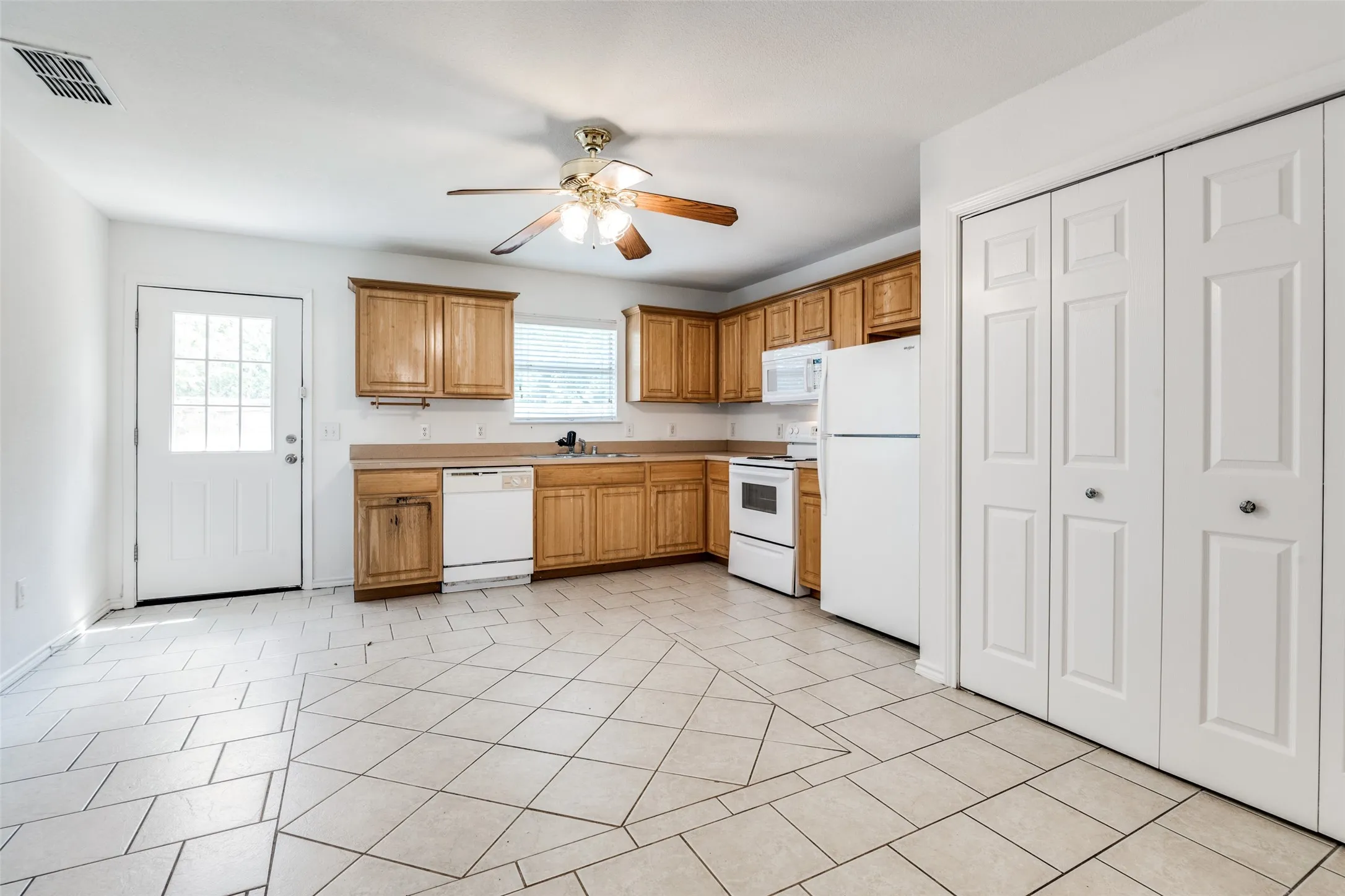 Kitchen featuring white appliances, plenty of natural light, sink, and ceiling fan