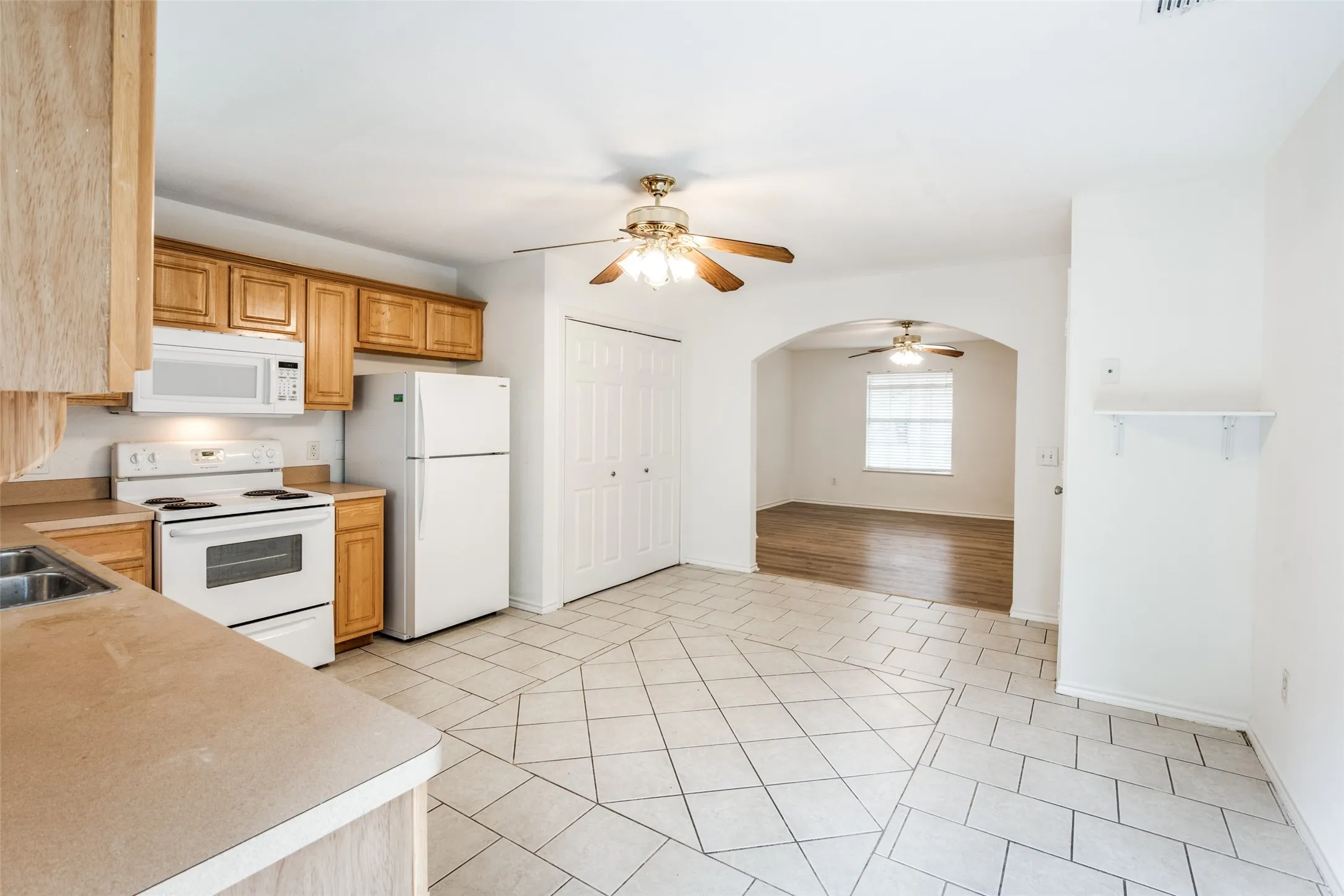 Kitchen with sink, ceiling fan, white appliances, and light hardwood / wood-style flooring