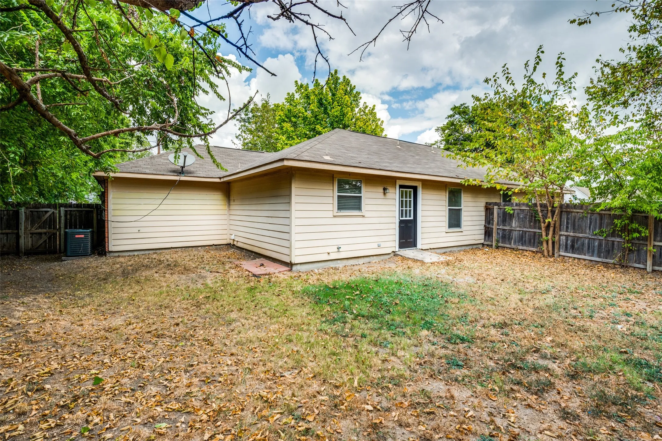 Rear view of house featuring cooling unit and a yard