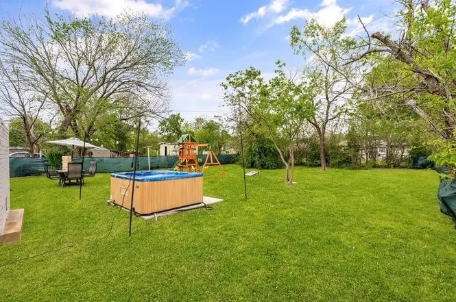 Fenced backyard featuring a hot tub on a concrete pad and mature trees