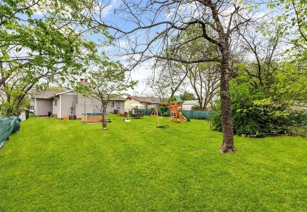 Expansive green lawn with mature trees and a hot tub