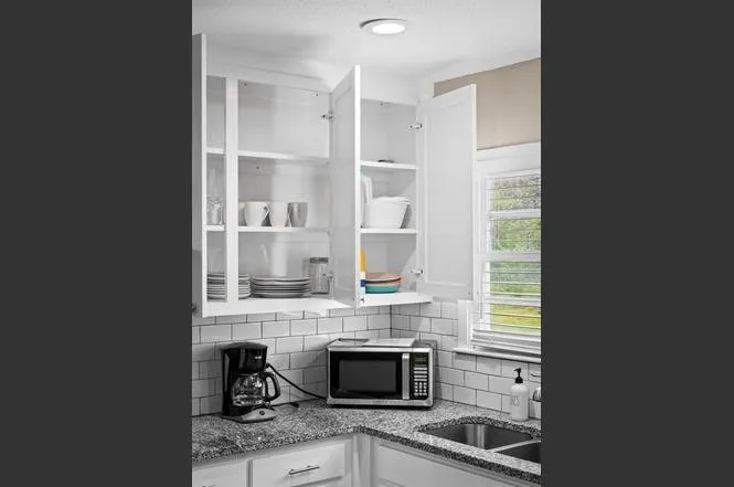White shaker-style cabinetry with ample storage, subway tile backsplash, granite countertops, and dual-basin sink