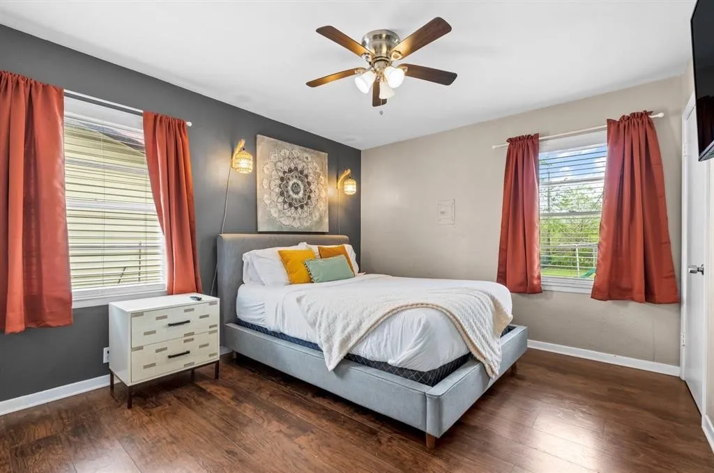 Wood-finish flooring, ceiling fan, and two windows with blinds
