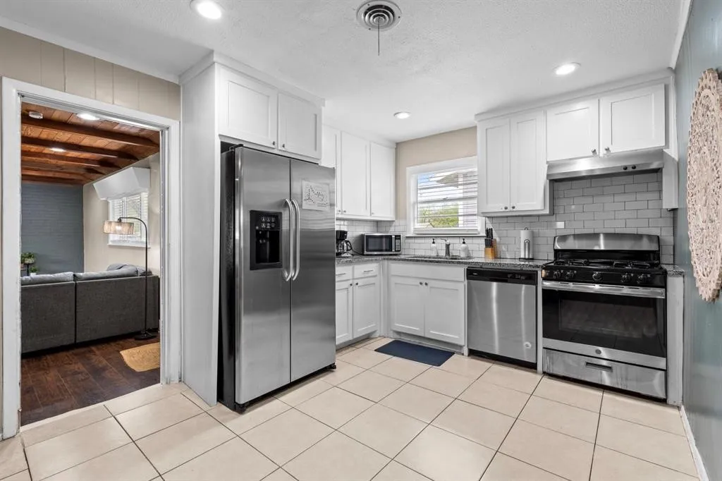 Kitchen featuring white cabinetry, stainless steel appliances, tile flooring, subway tile backsplash, and recessed lighting