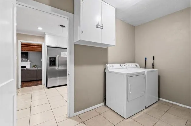Utility area with overhead cabinetry and tile flooring