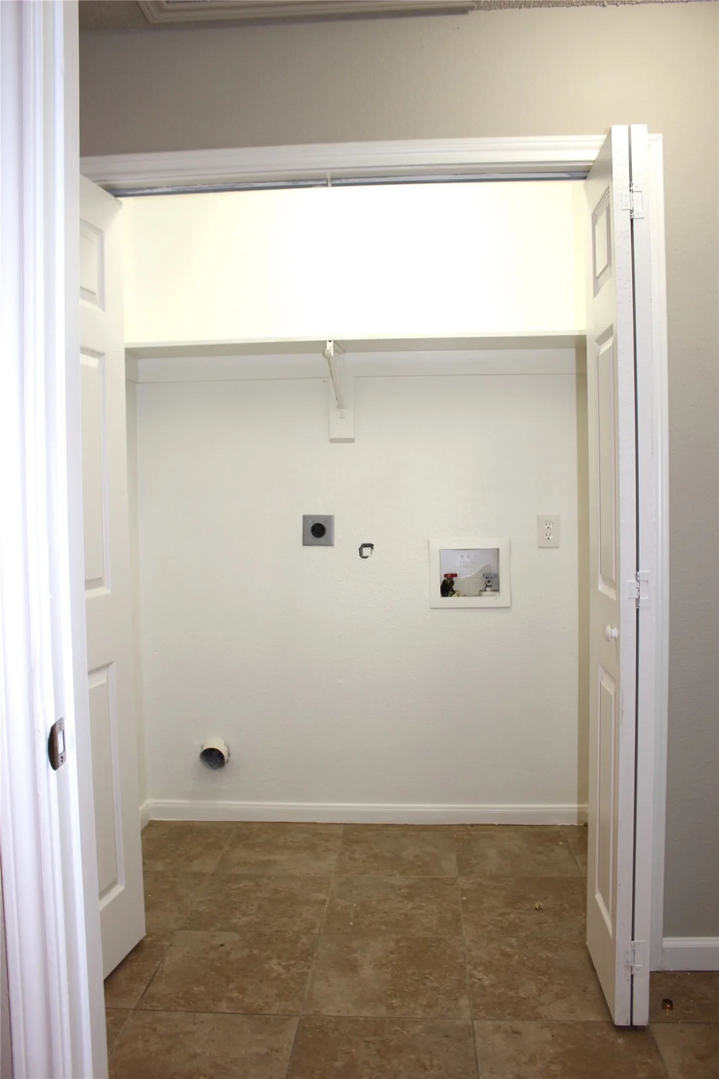 Laundry closet with a tiled floor, white walls, and bi-fold doors