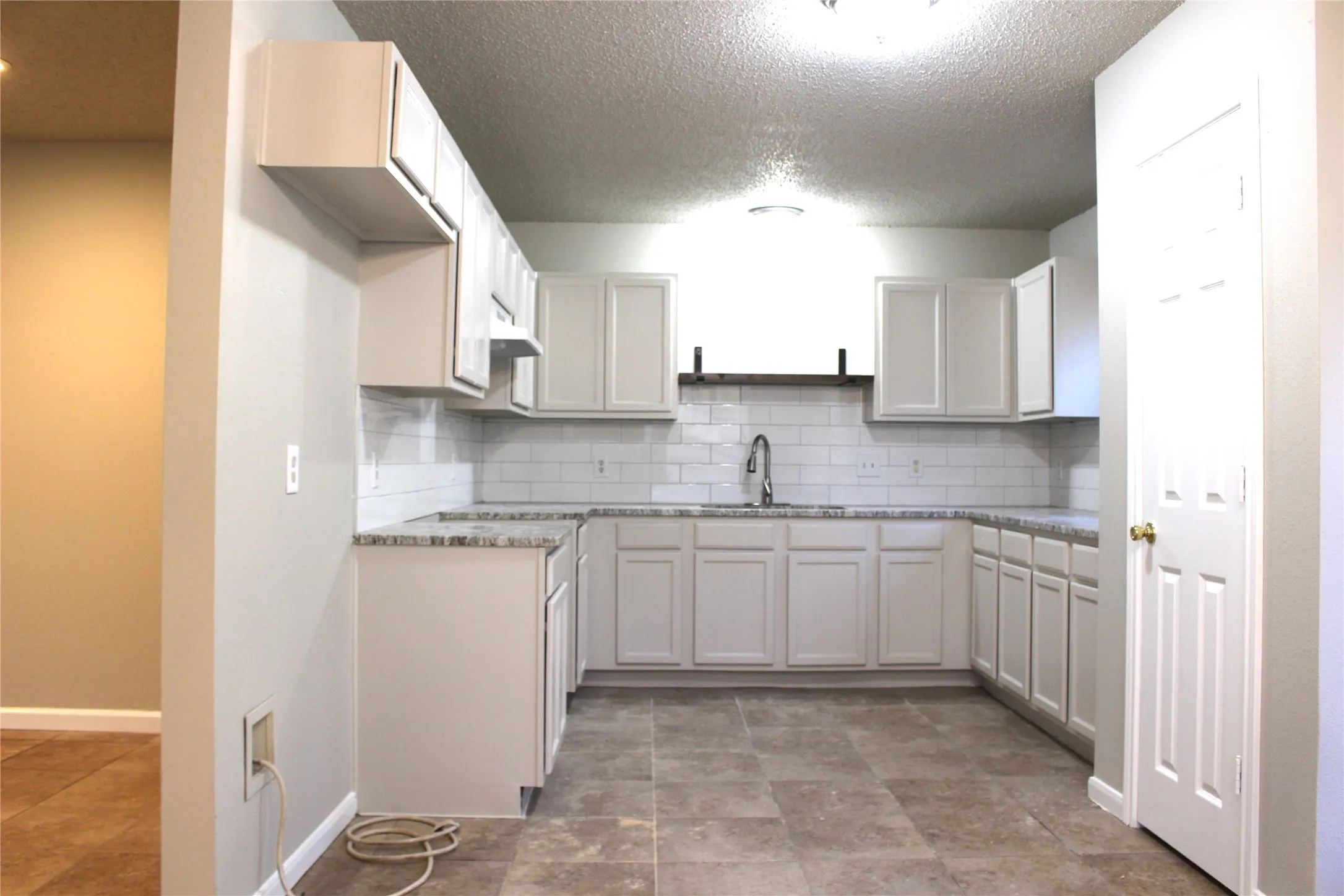 U-shaped kitchen layout with white cabinetry, light-toned countertops, and a subway tile backsplash