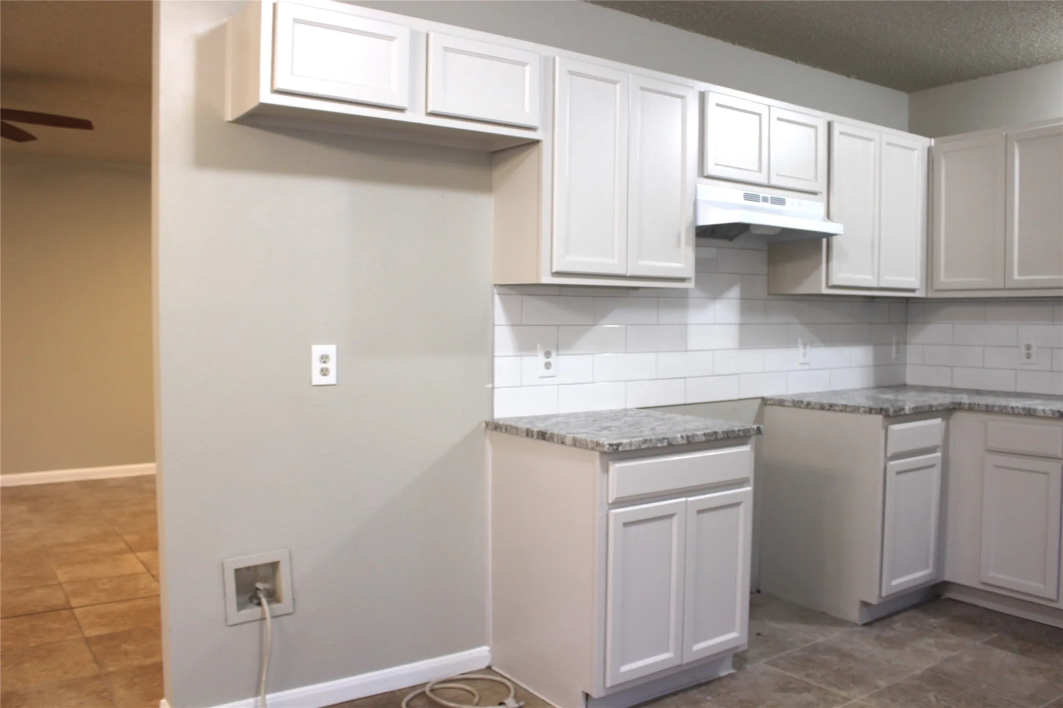 White shaker cabinetry, subway tile backsplash, granite-style countertops, and tile flooring