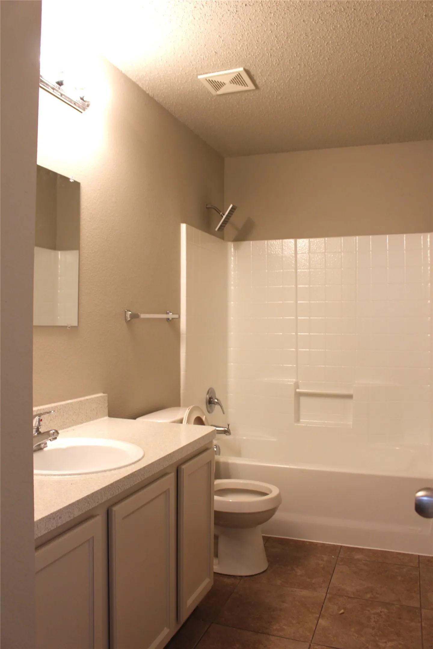 Bathroom featuring a single vanity with an integrated sink, a white shower-over-tub combination, and tiled flooring