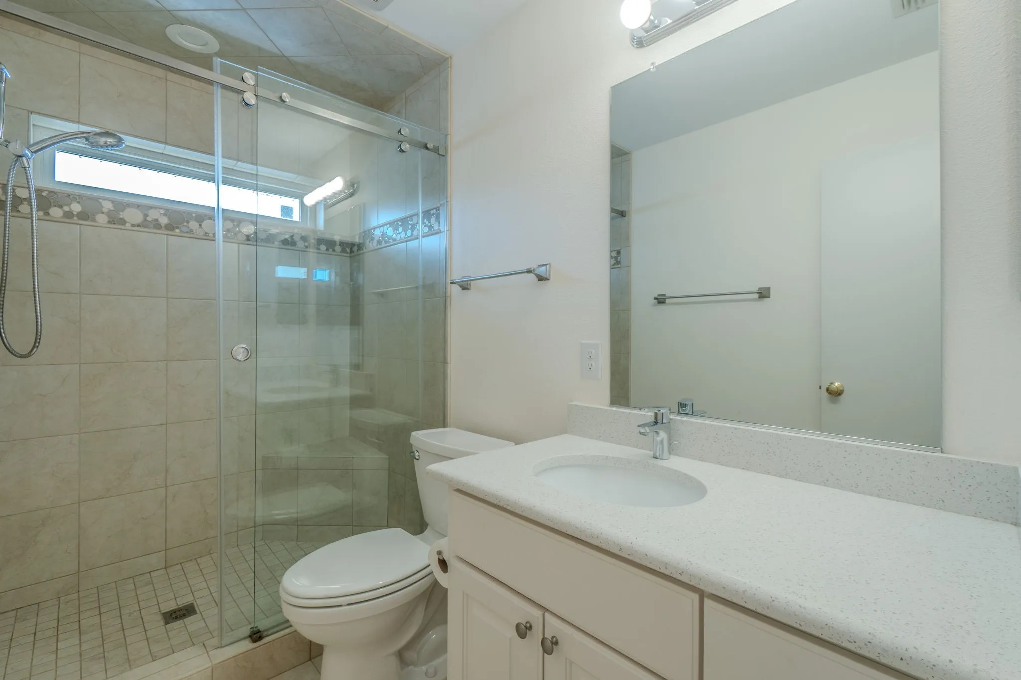 Secondary Primary Bath upstairs Walk-in shower with clear glass enclosure, tile surround, and decorative accent band