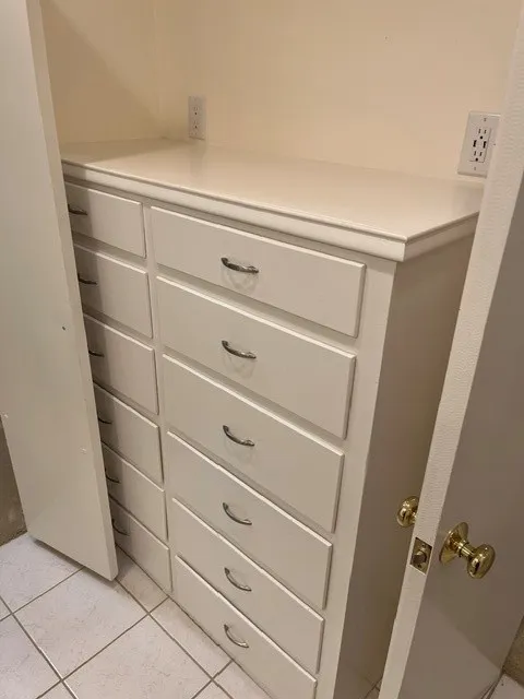 Built-in white cabinetry featuring multiple drawers with metal pulls, a white countertop, and tile flooring