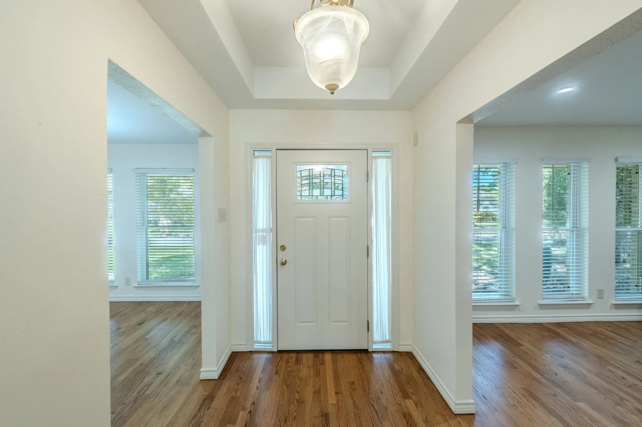 Entryway featuring wood-finish flooring, a white paneled door with decorative glass, and a coffered ceiling with a semi-flush mount light fixture