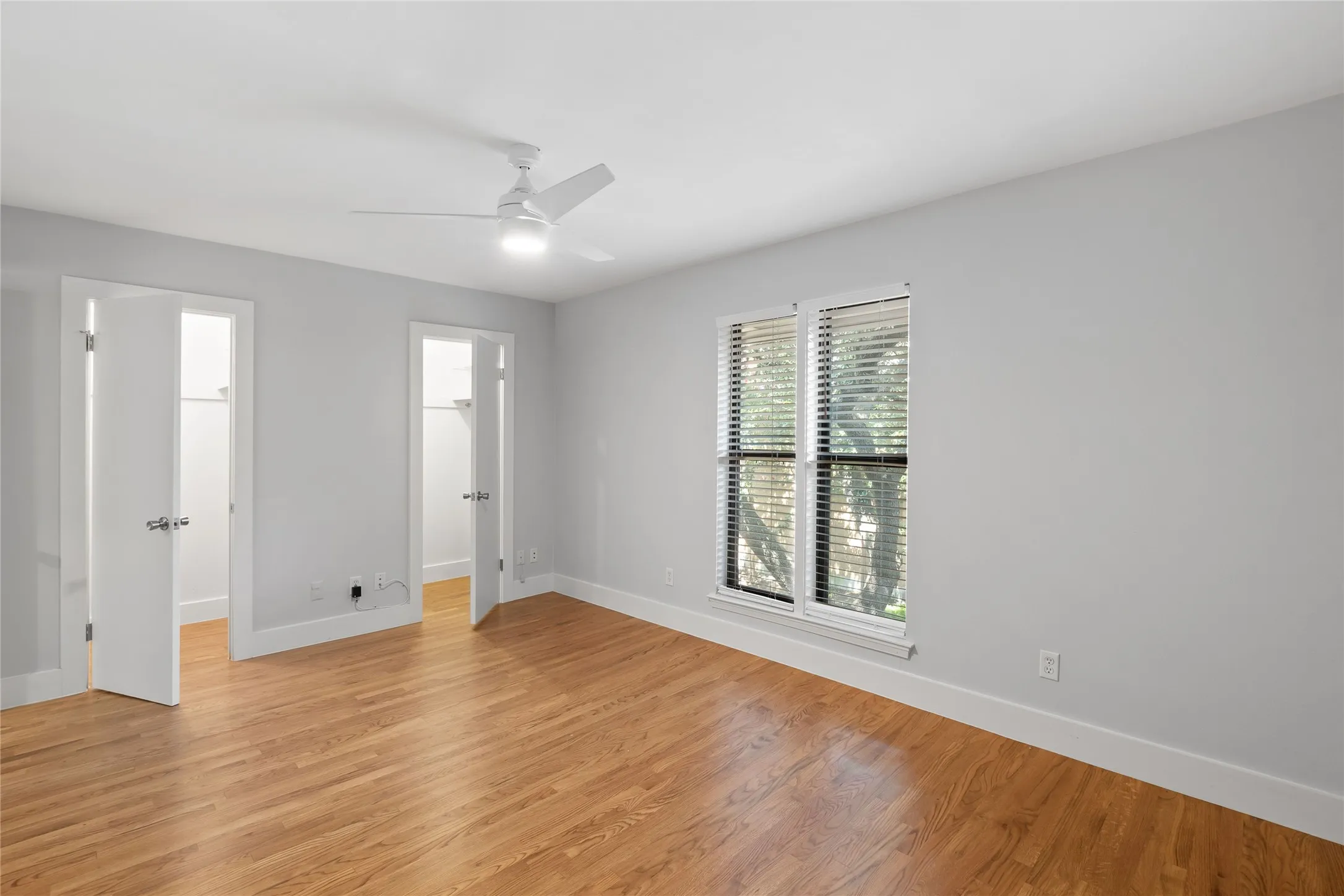 Unfurnished bedroom with a walk in closet, light wood-style flooring, and a ceiling fan